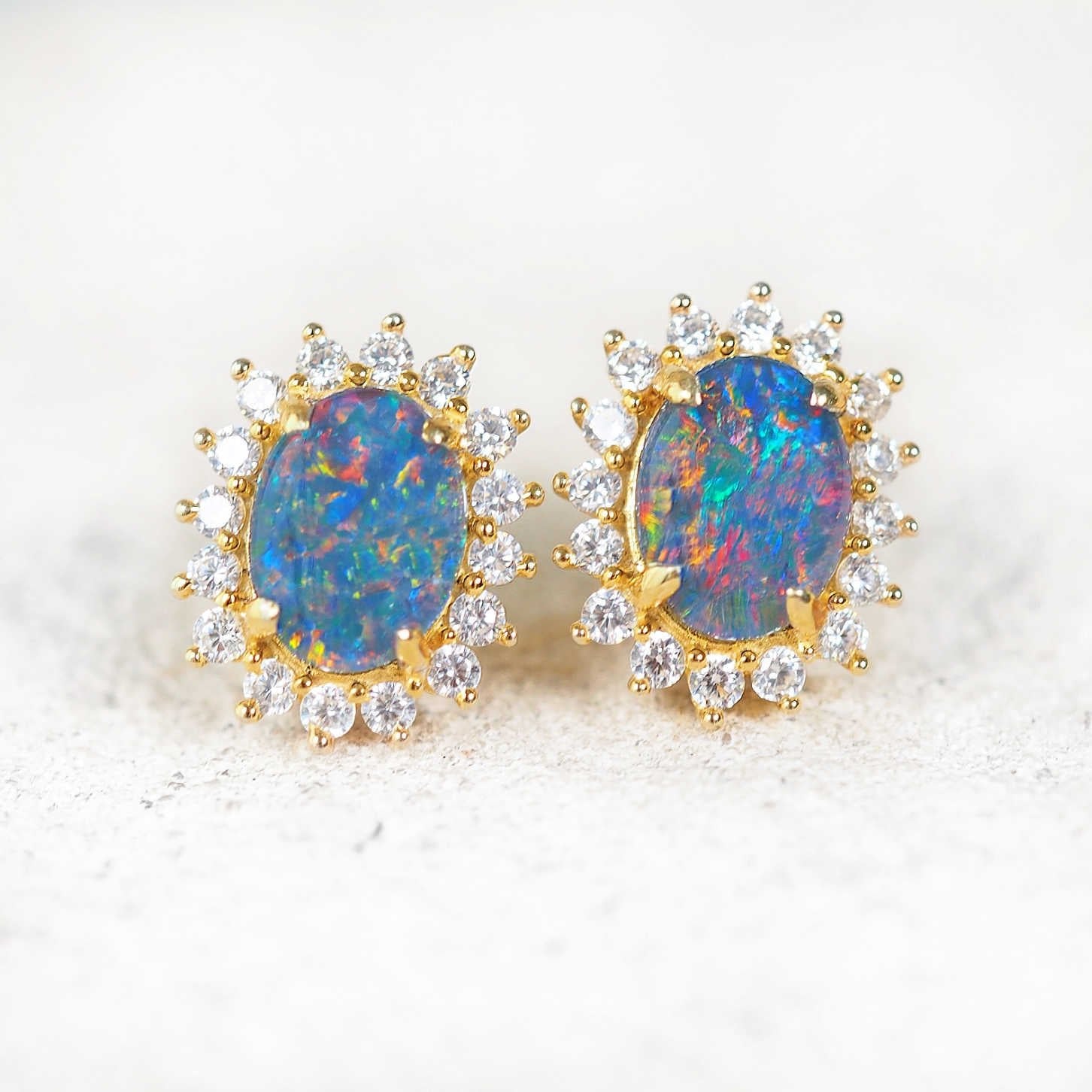 Close-up of gold plated silver earrings with vivid multi-colour opals and cubic zirconia halo.