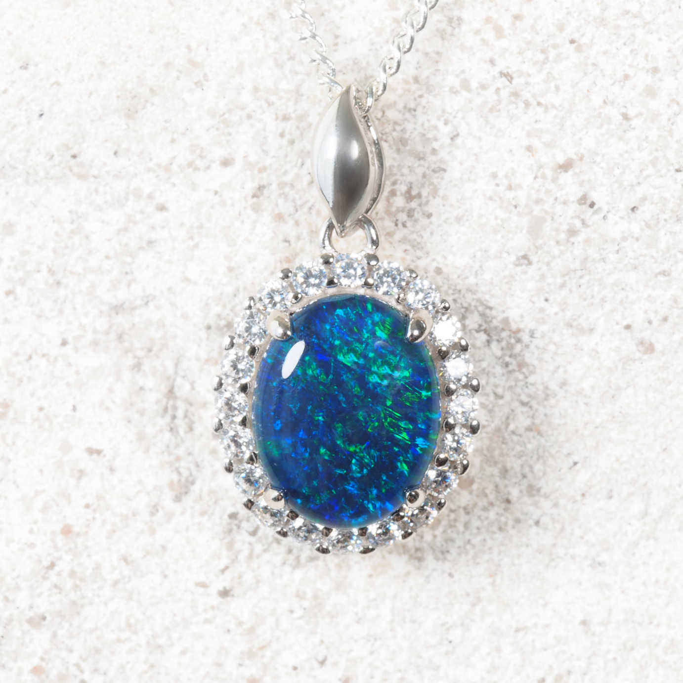Opal pendant with silver chain on a textured white background