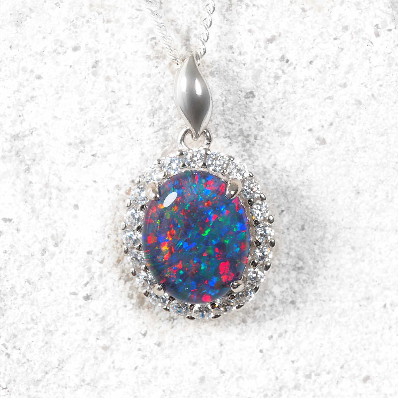 Opal pendant with silver chain on a textured white background