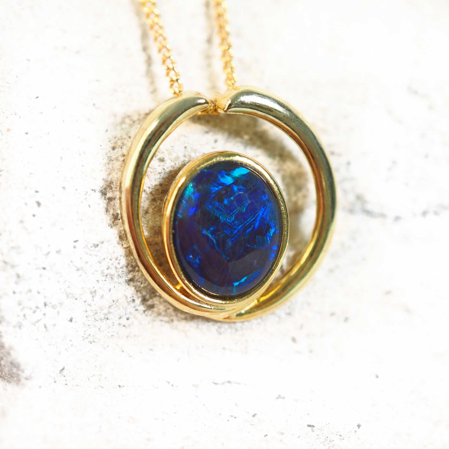 Modern gold opal necklace featuring oval-shaped blue and green Australian triplet opal in open circle setting