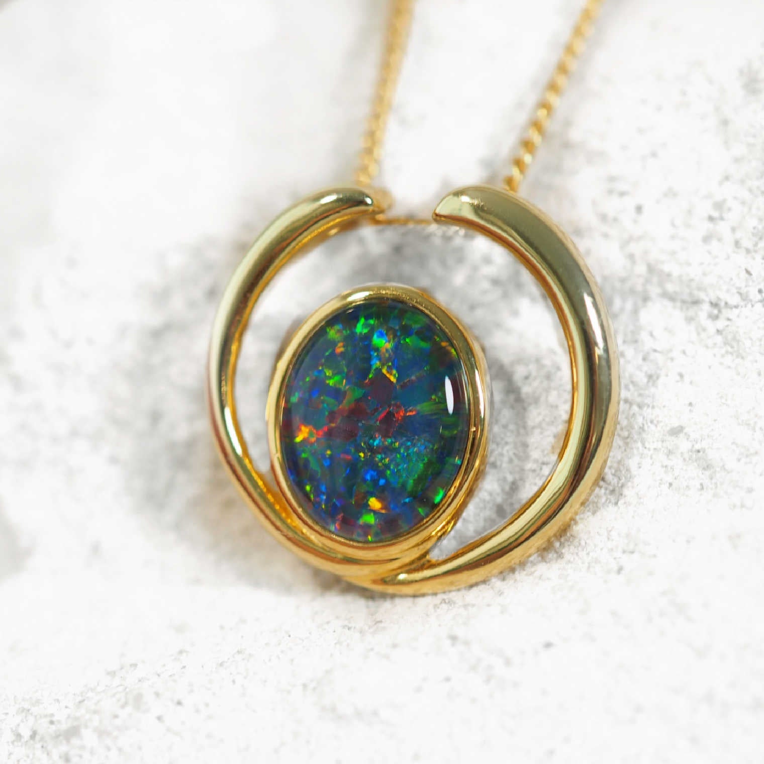 Opal pendant with gold setting on a white background