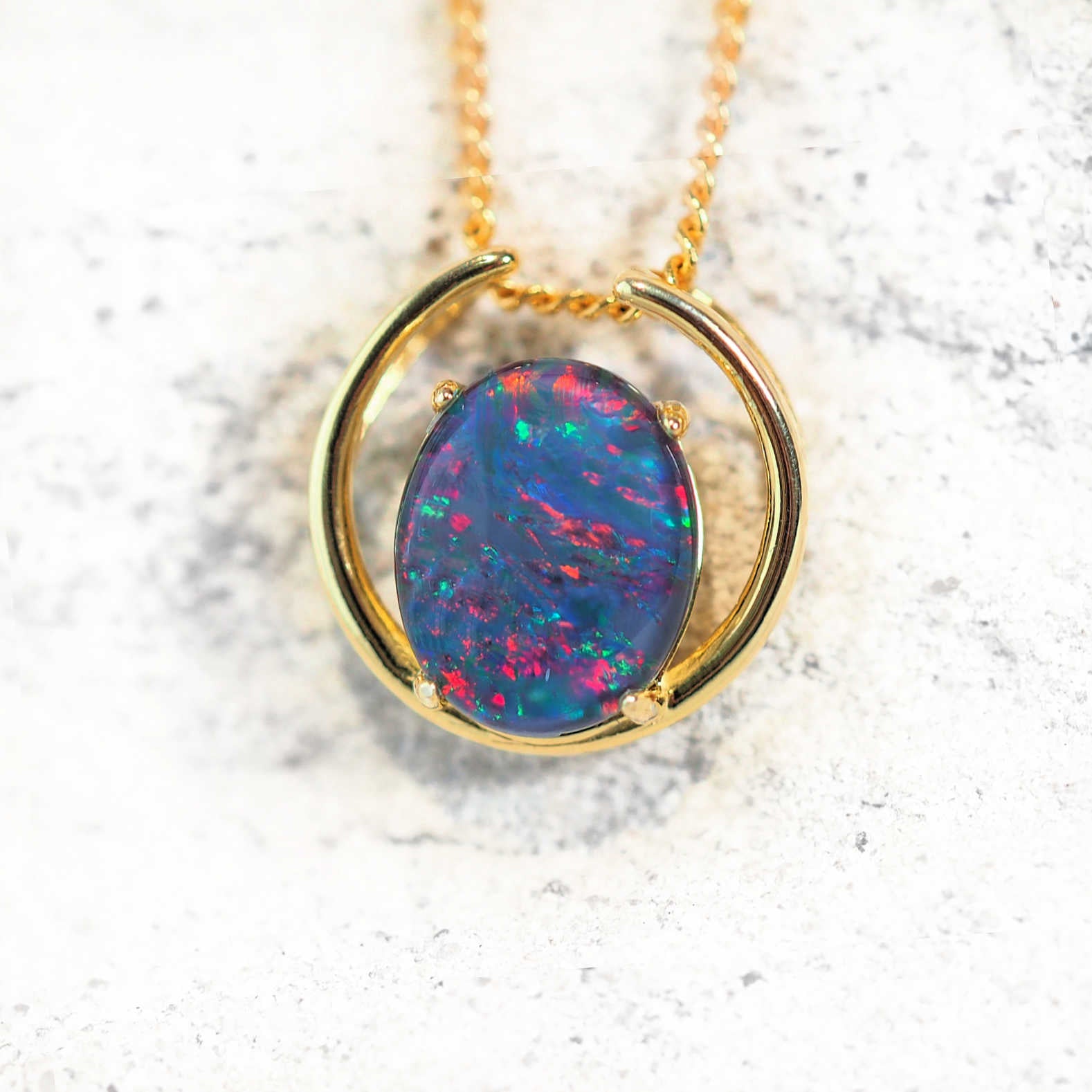 Gold-plated silver open-circle opal pendant necklace with claw-set oval Australian triplet opal in multi-colour or blue-green, on matching chain.