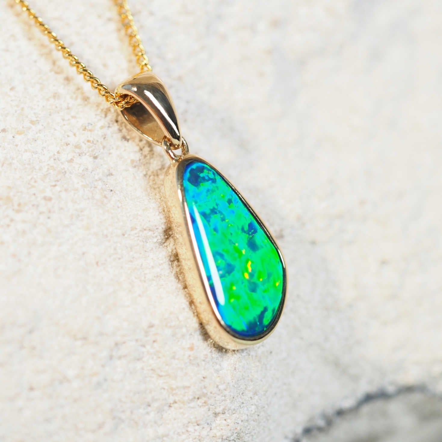gold opal pendant set with a green and blue doublet opal