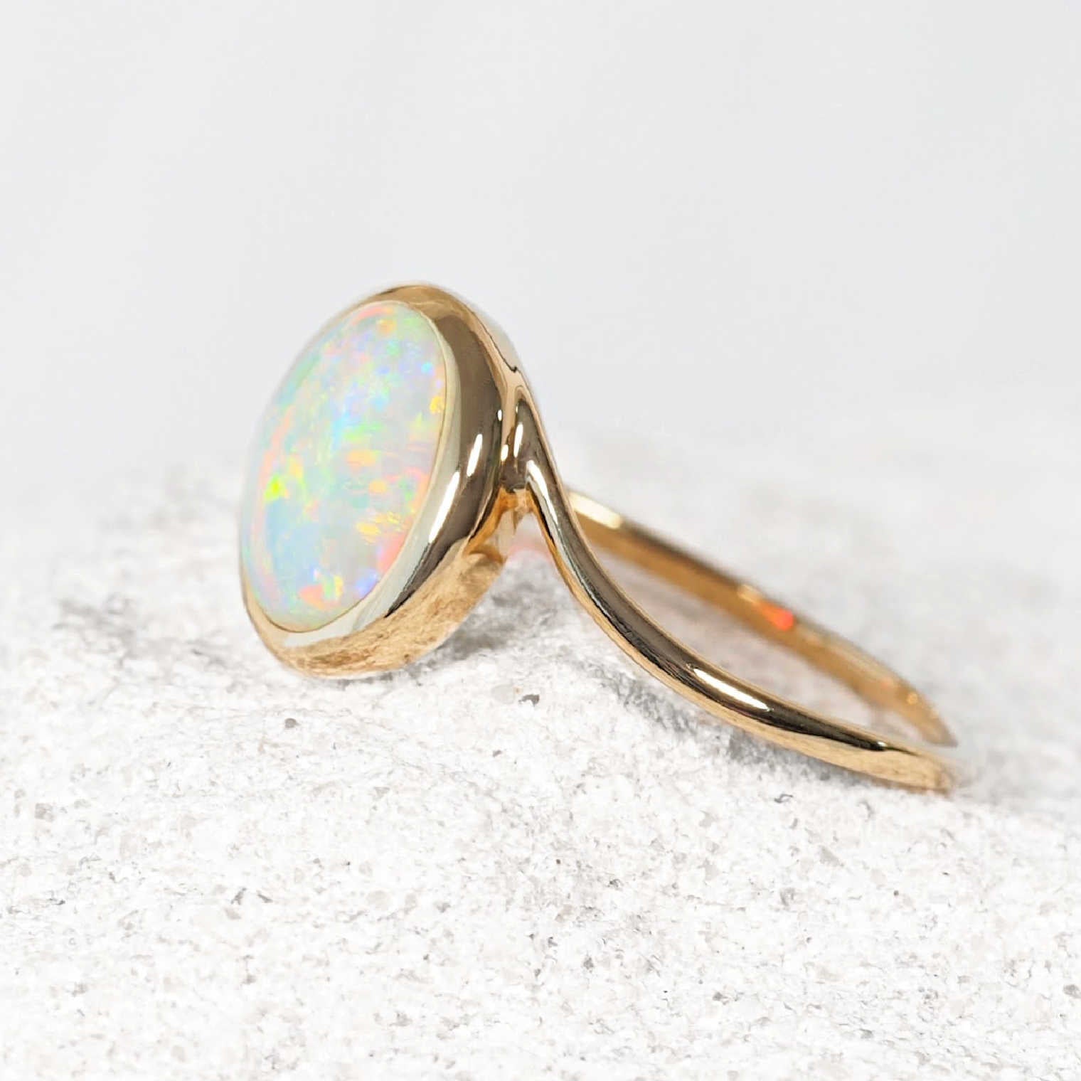 Australian crystal opal ring in 14ct yellow gold with a genuine oval Coober Pedy opal displaying natural green, blue and gold colour