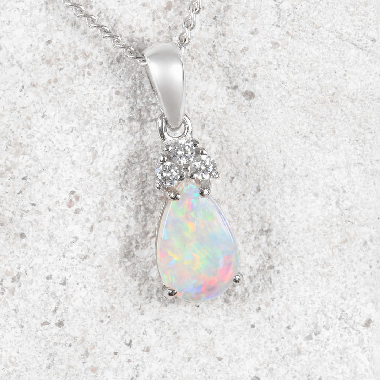 Colourful opal pendant necklace on a textured white background