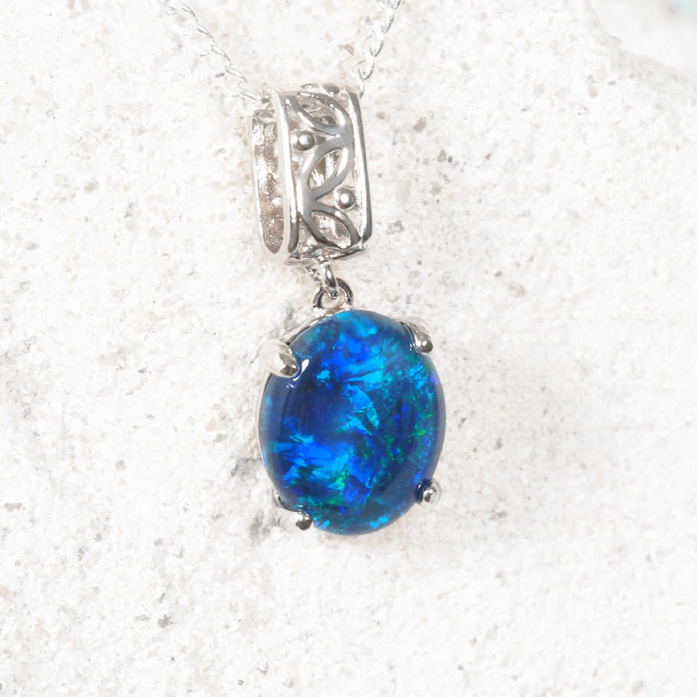 Blue opal filigree silver pendant on a silver chain against a white background