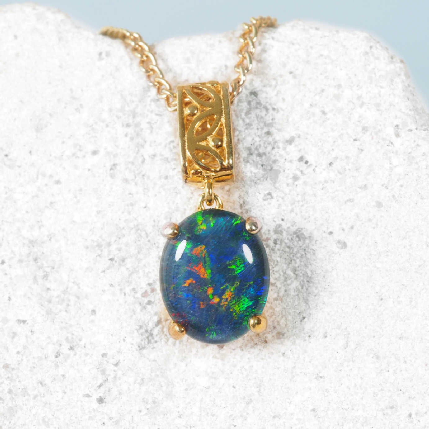 Opal pendant on a gold chain against a white background