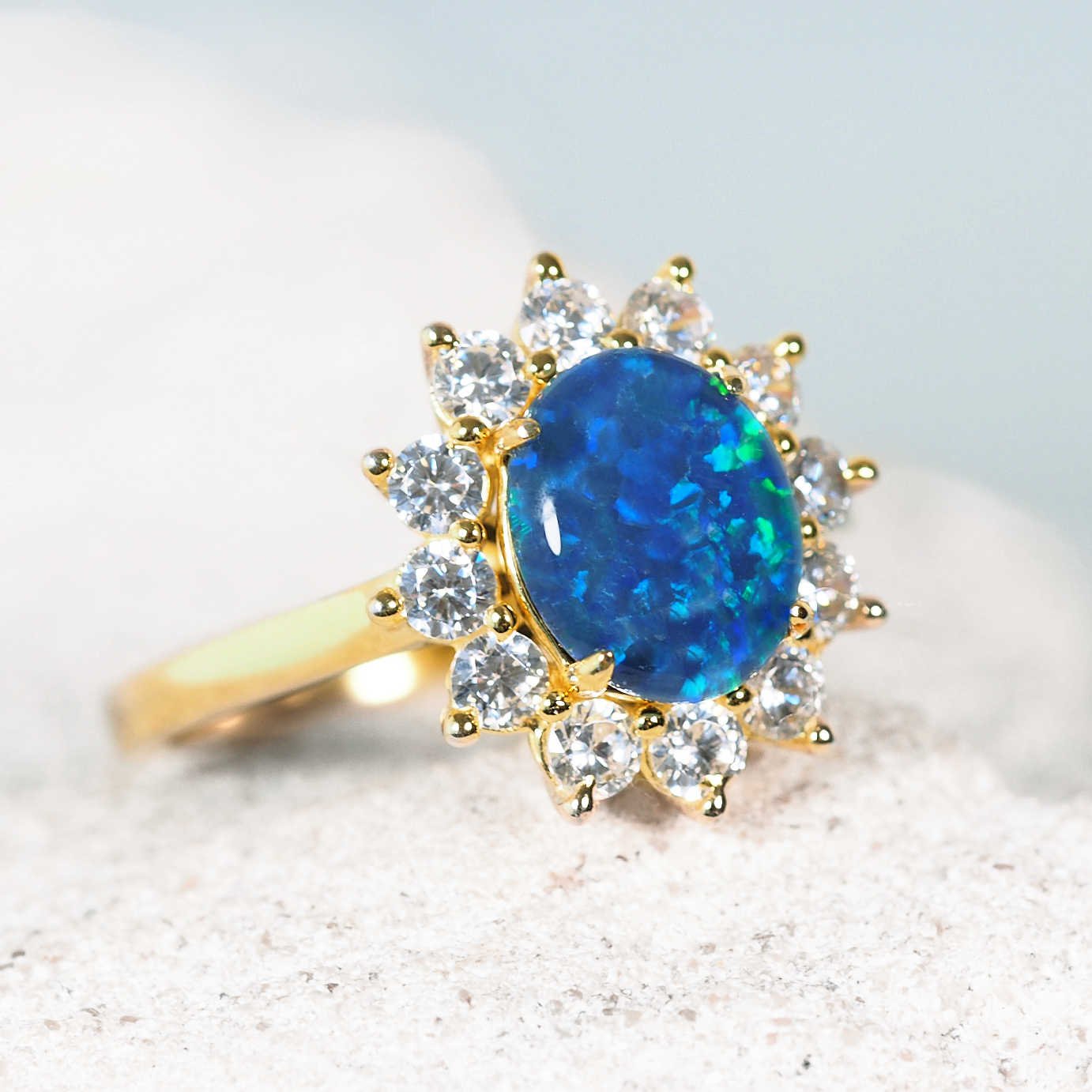 Gold ring with a blue opal stone and diamond accents on a light background