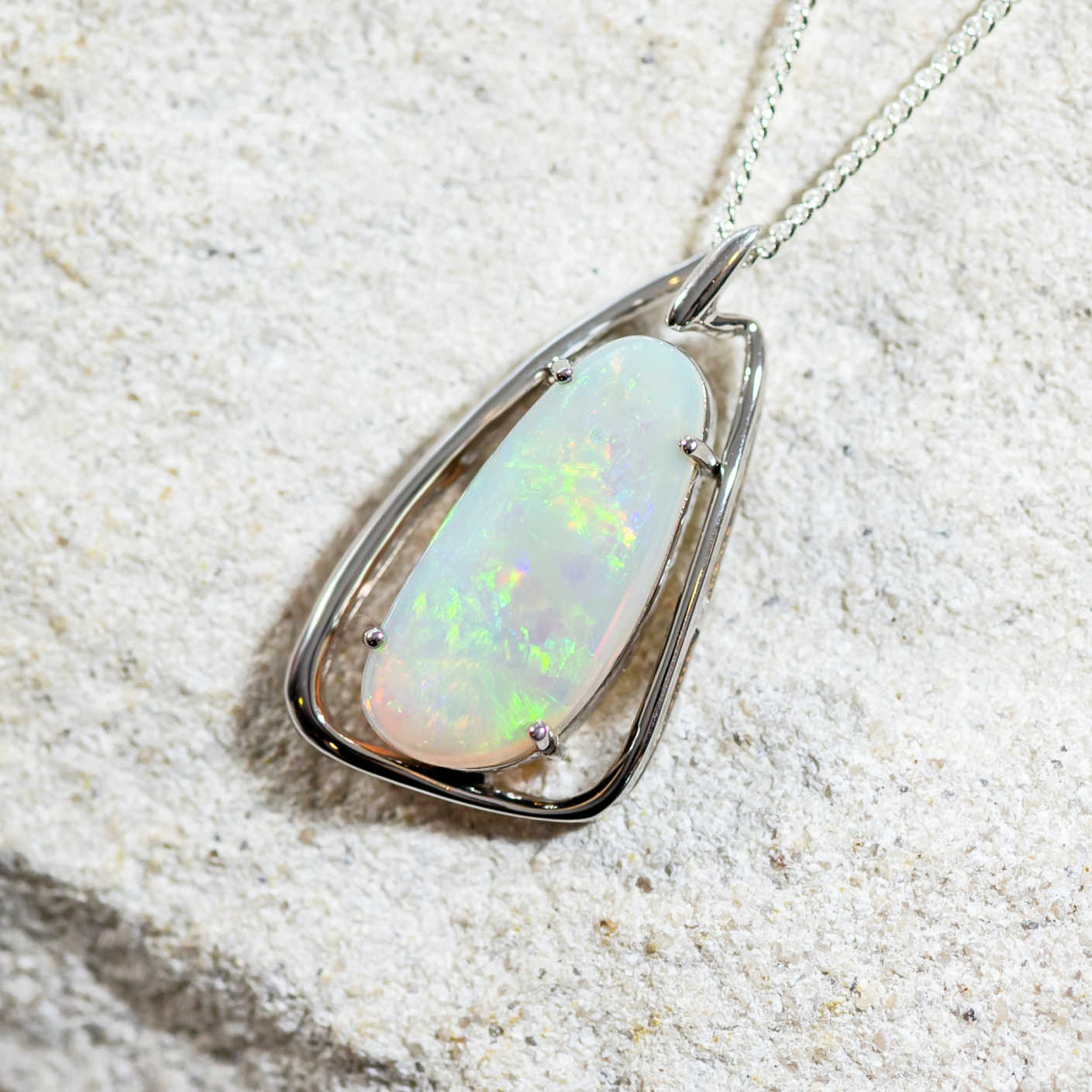Contemporary sterling silver necklace pendant claw set with a multi-coloured freeform-shaped South Australian solid crystal opal.
