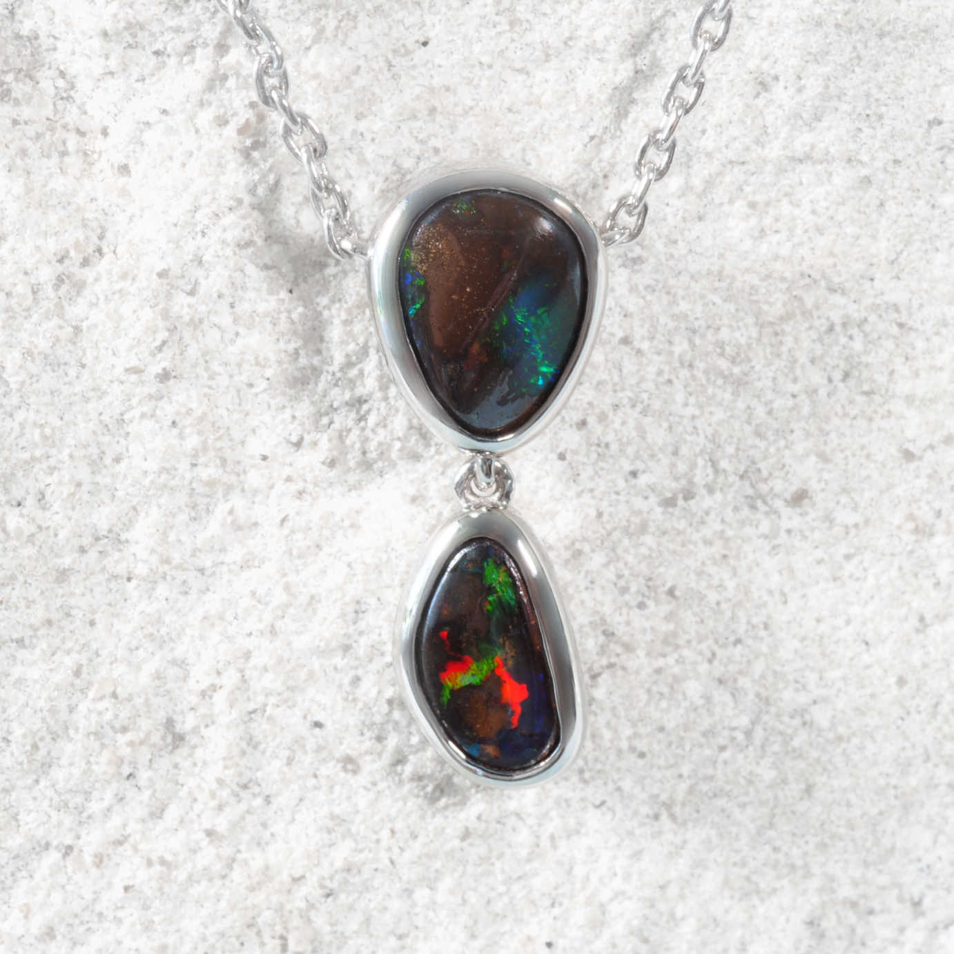 Boulder opal pendant necklace on a textured white background