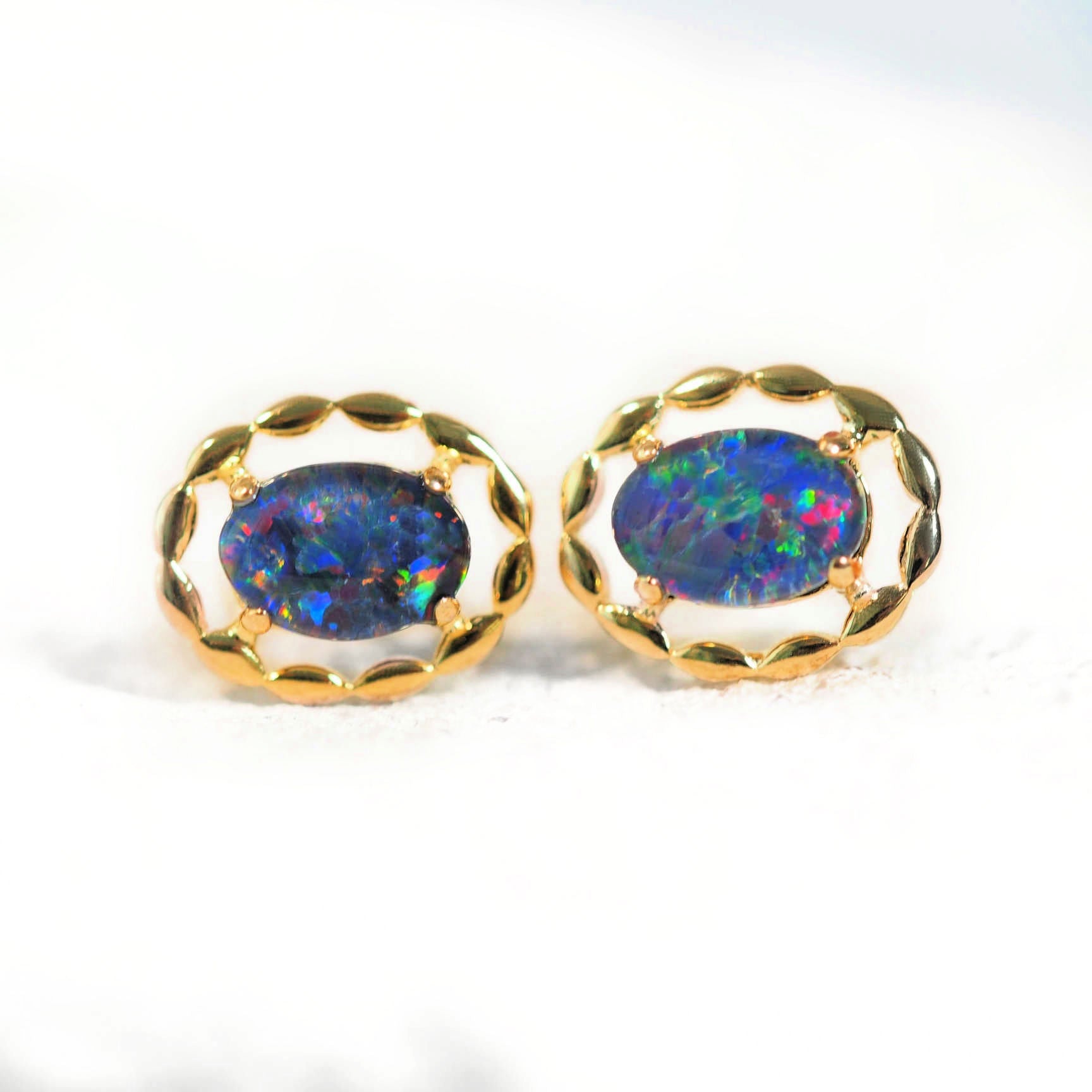Pair of opal earrings with gold frames on a white background