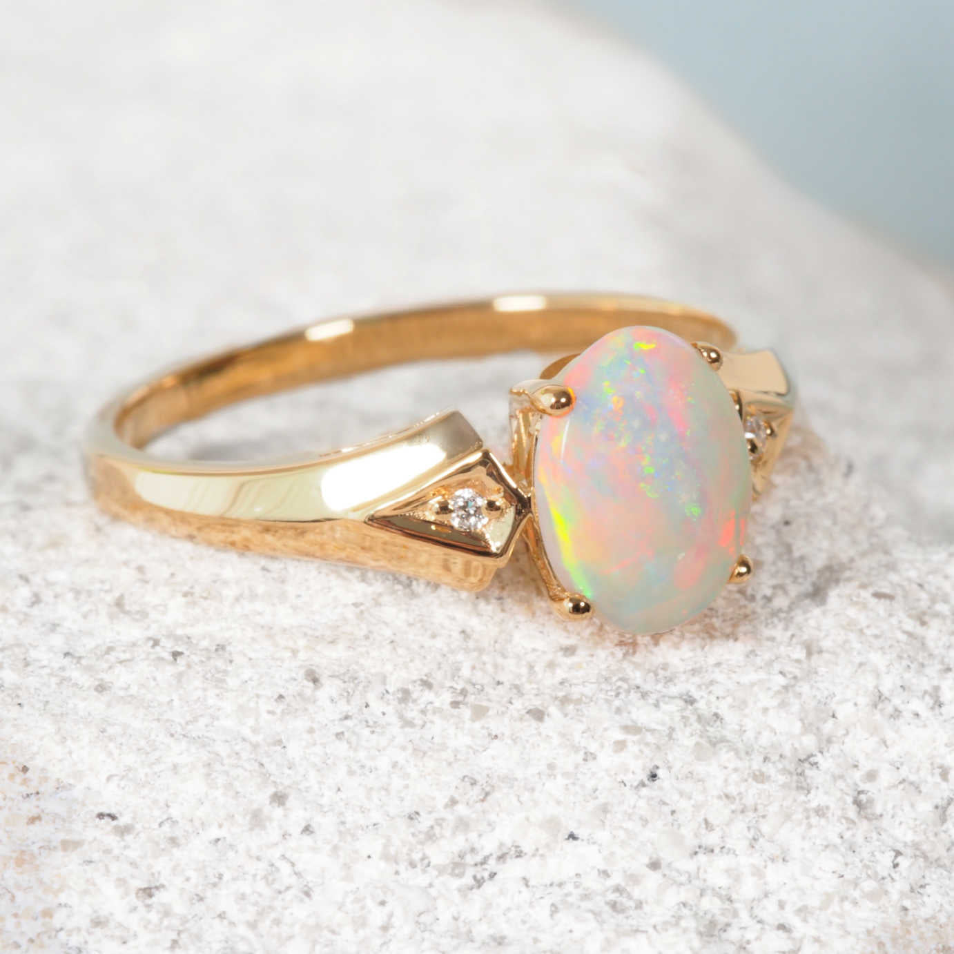 Gold opal ring with a large opal stone on a textured surface