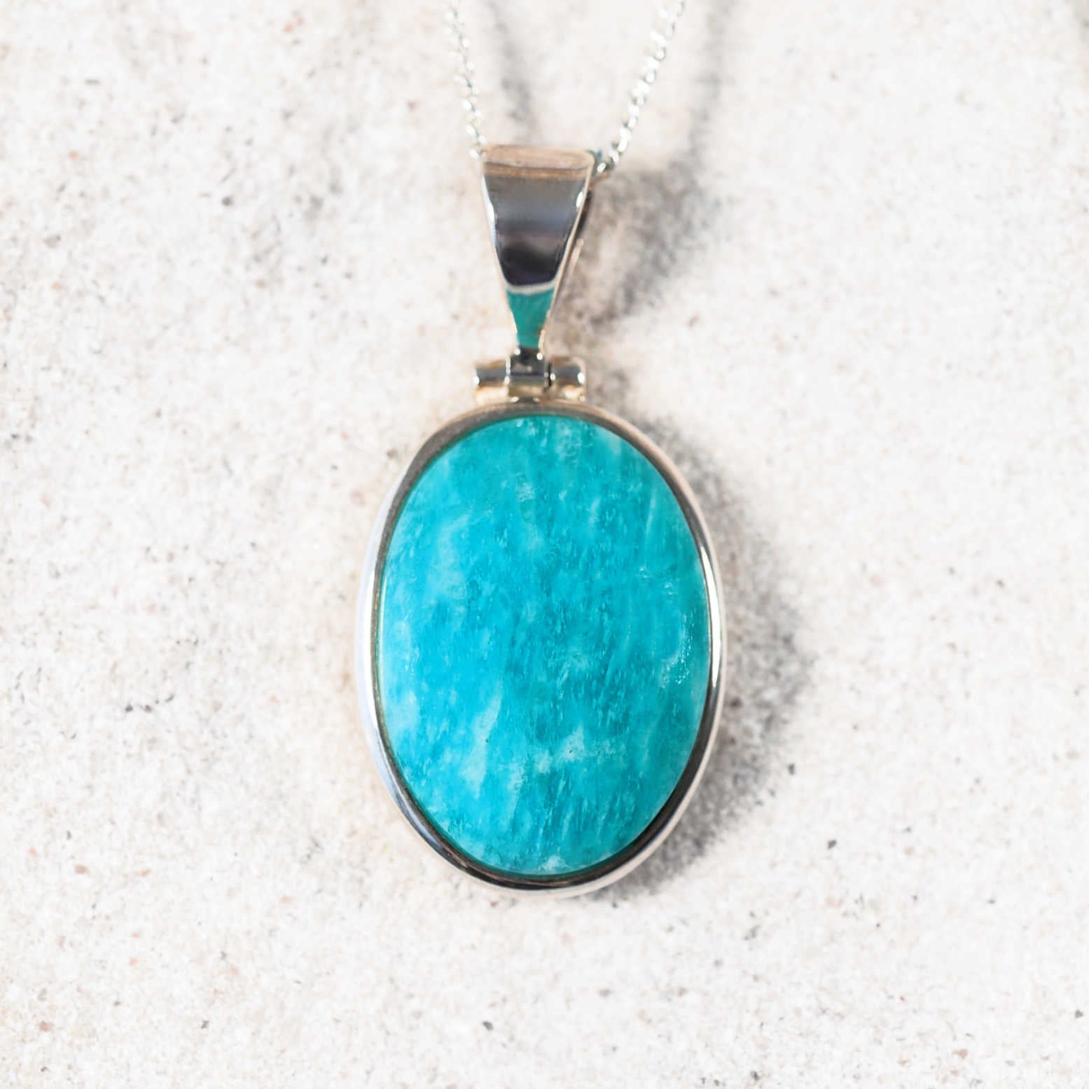The 'Inata' Amazonite pendant with circular cabochon set in polished silver, highlighting its calming blue-green hues
