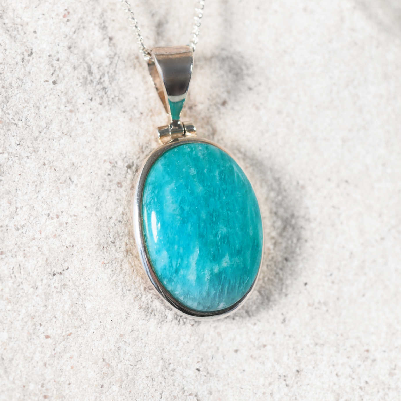 Close-up of the 'Inata' pendant showing a smooth Amazonite cabochon secured in a refined silver frame