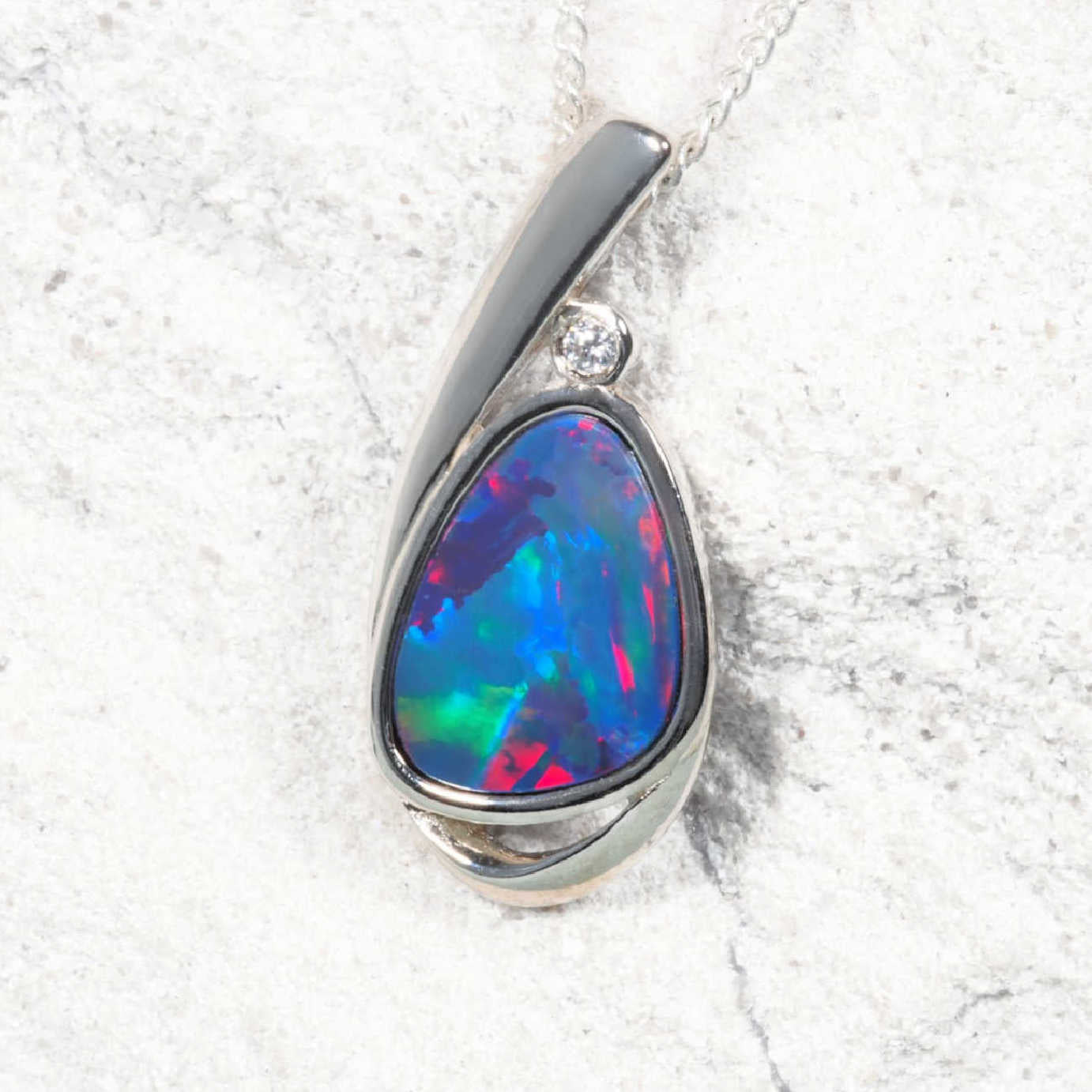 Opal pendant with silver setting on a textured white background