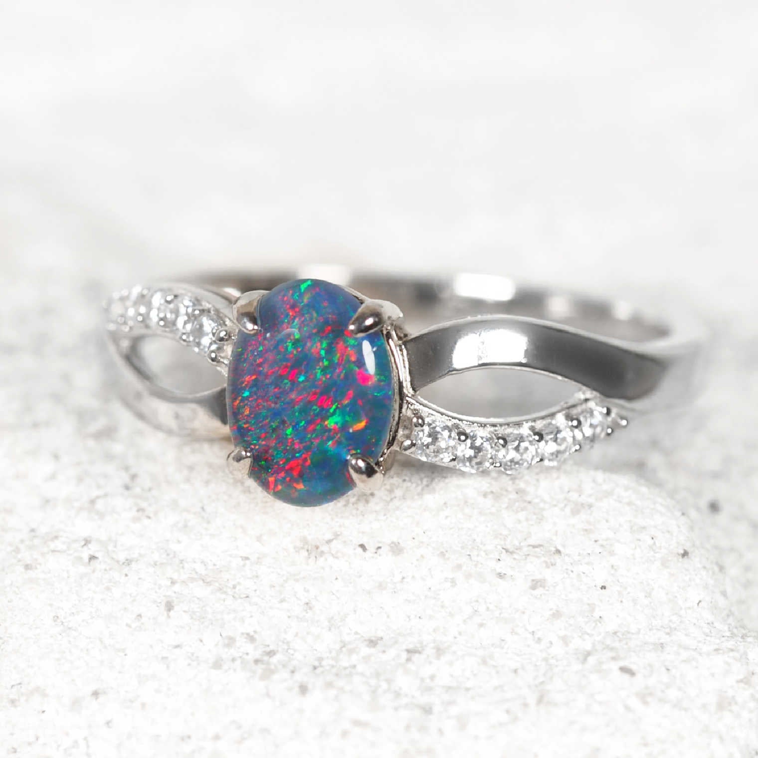 Silver ring with a colorful opal stone on a white background