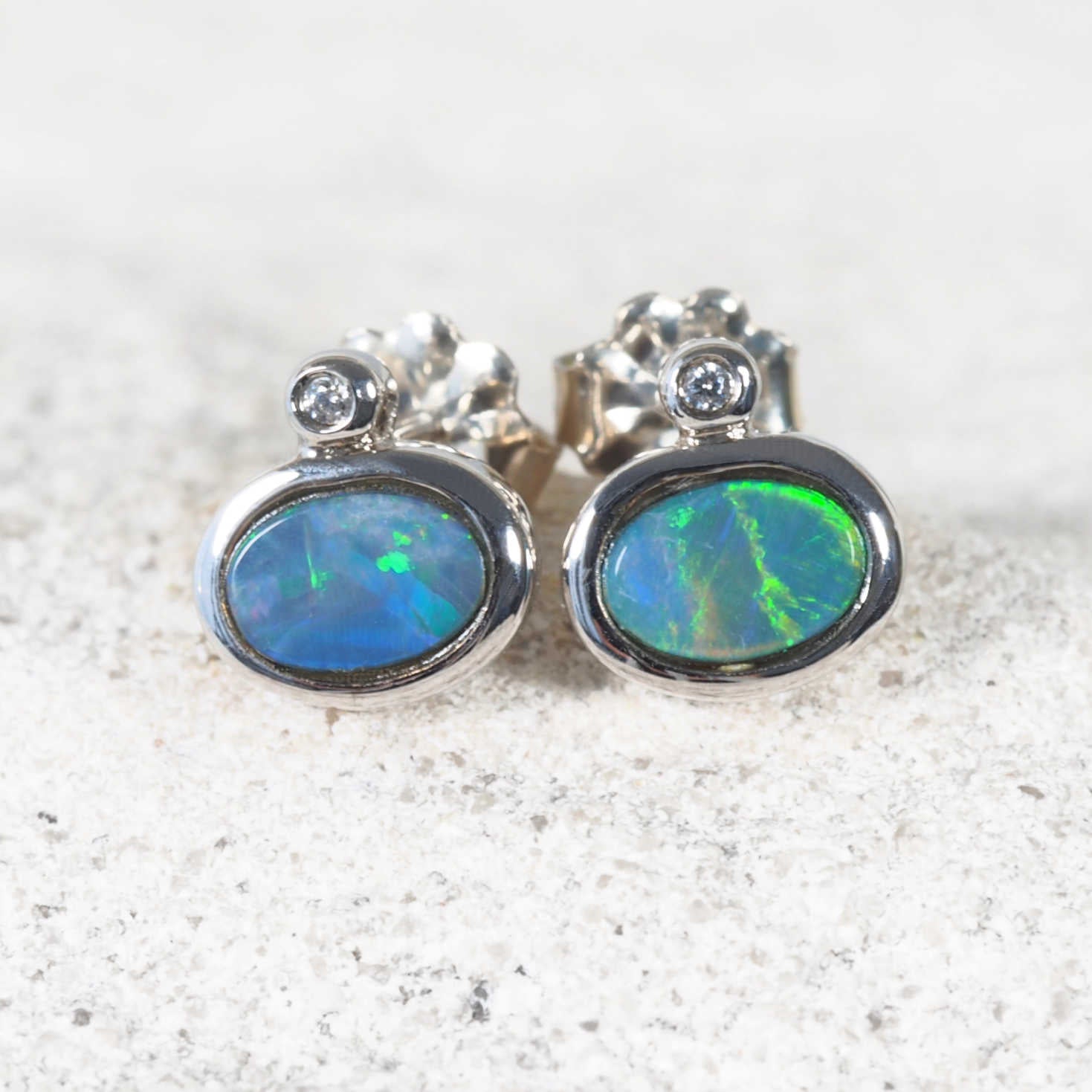 Oval bezel-set Australian doublet opal earrings with flashes of blue, green and pink