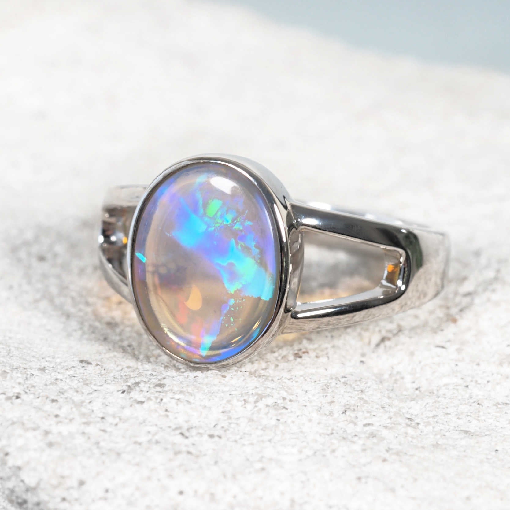 Bezel-set crystal opal ring glowing with vivid hues