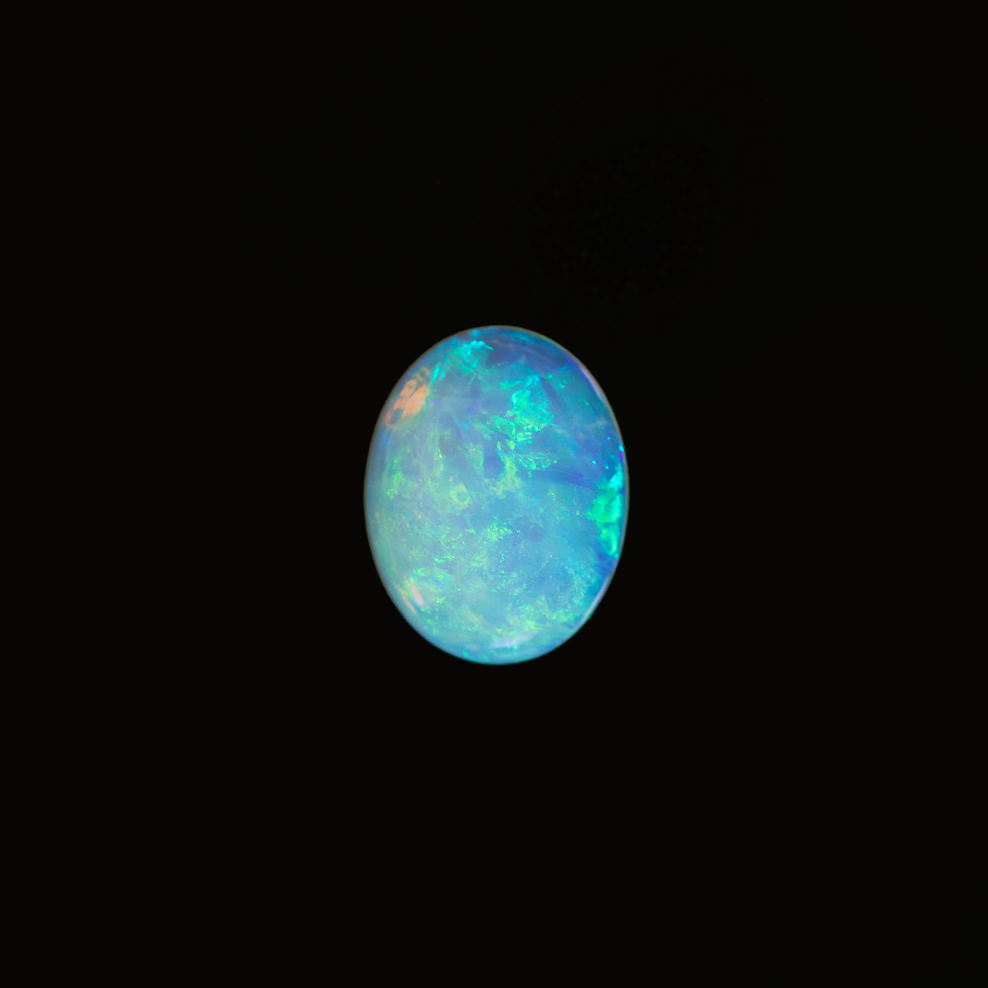 Opal stone with multicolored fluorescence on a black background