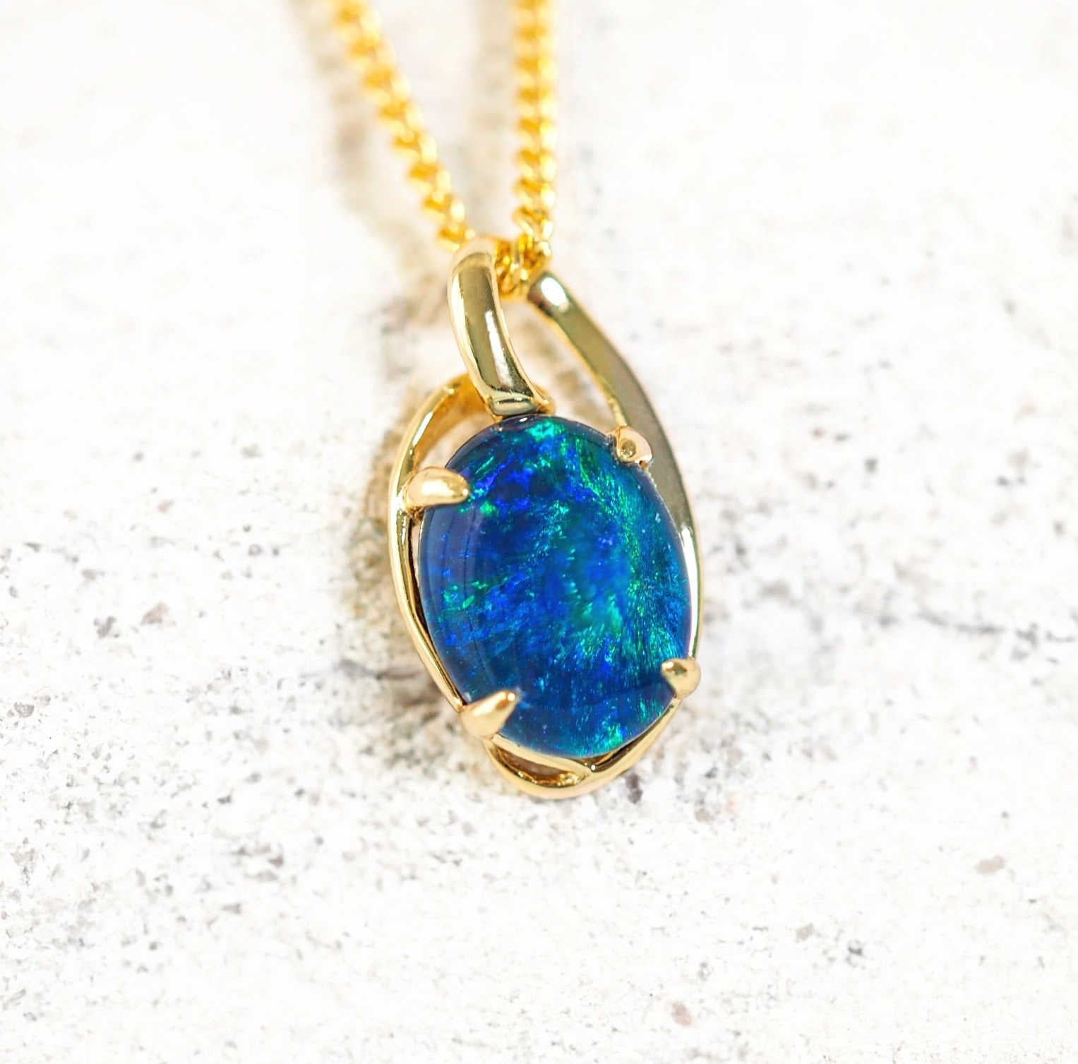 Luxurious gold-plated silver opal necklace pendant, 'Kylan Blue,' with claw-set oval Australian triplet opal in vibrant blue and green tones inspired by the Australian coastline.