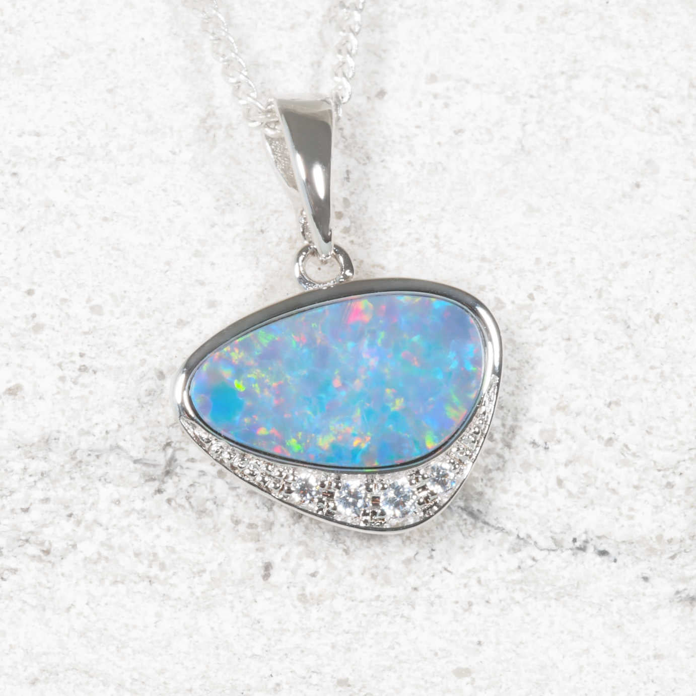 Opal pendant with silver frame on a textured white background