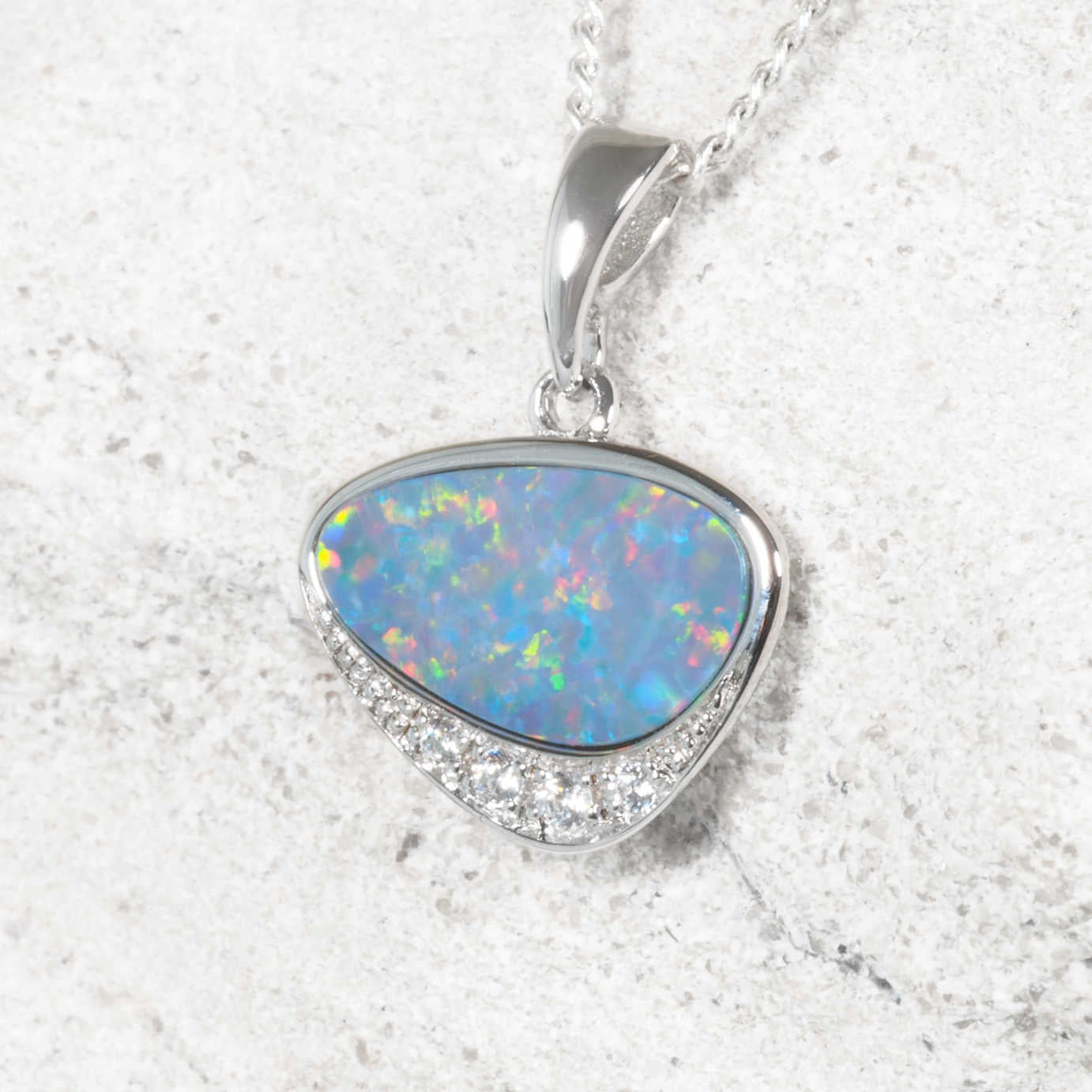 Opal pendant necklace on a textured white background