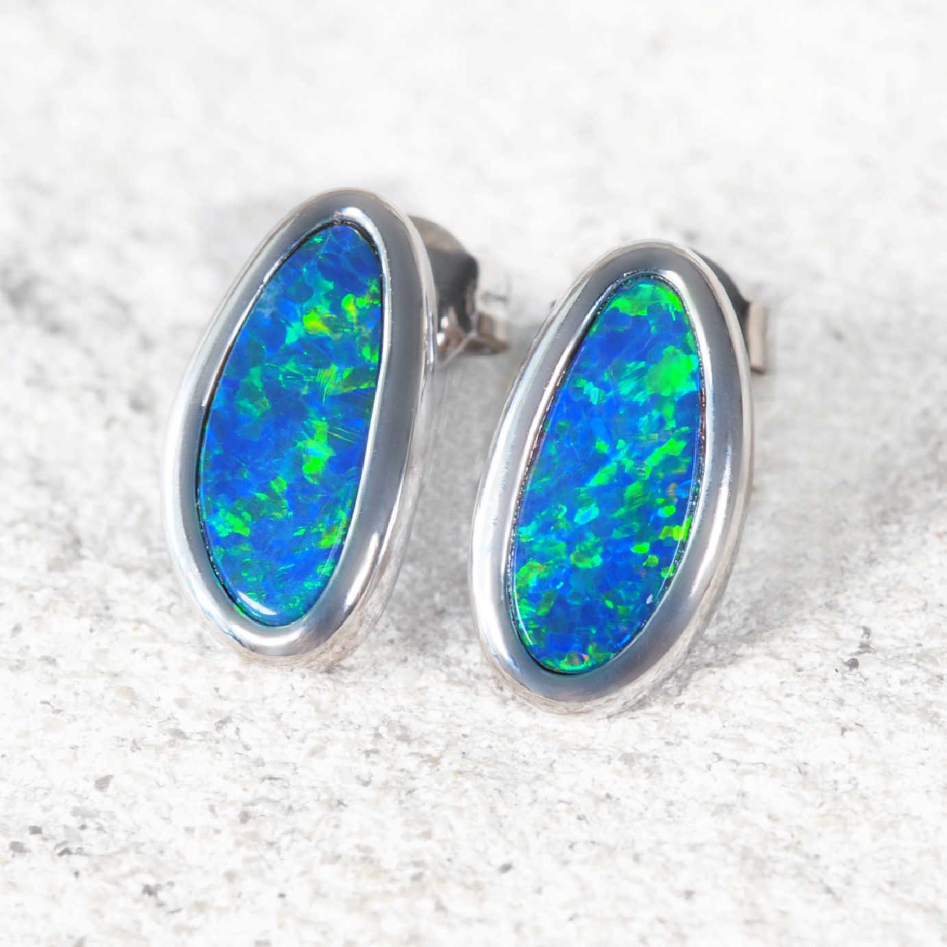 Australian pal earrings with white gold setting on a textured white background