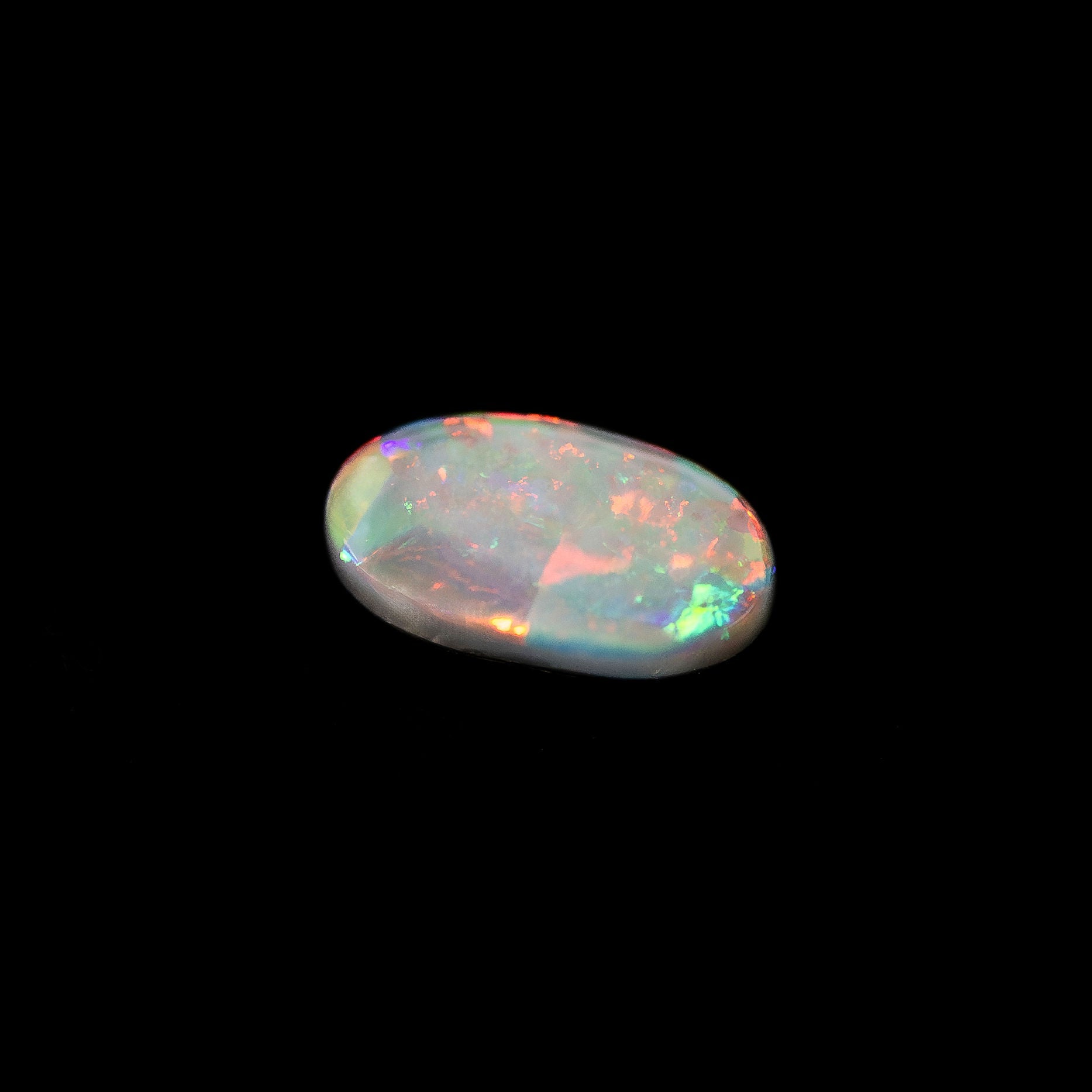 Black Opal stone with multicolored play of light on a black background