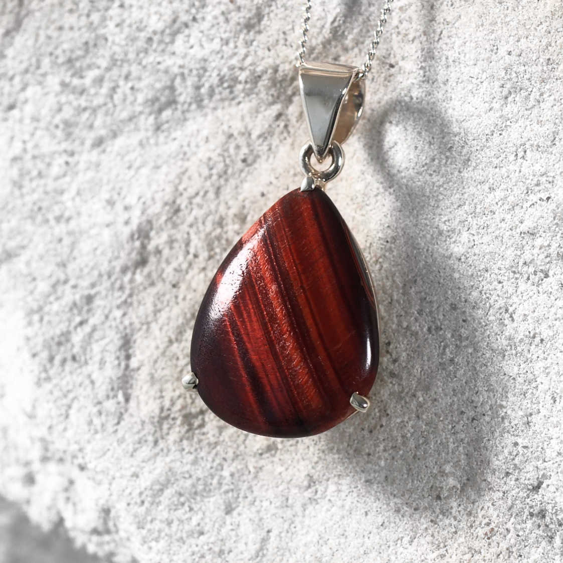Elegant Red Tiger Eye teardrop pendant in a silver bezel with claw details.