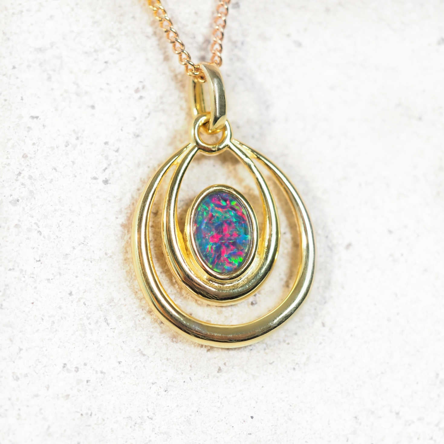 Gold-plated silver opal pendant necklace with bezel-set Australian triplet opal and double ring design on matching chain.