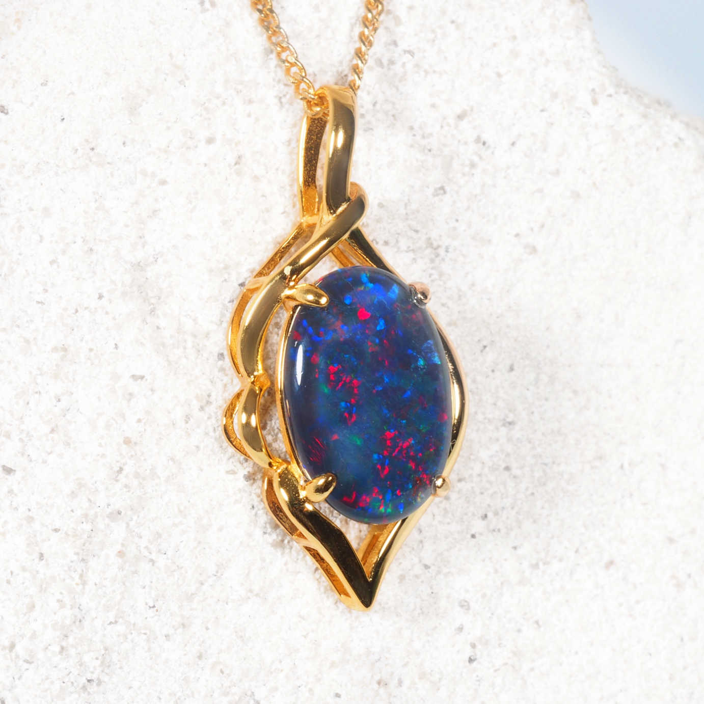 Gold plated silver opal pendant with a blue opal stone on a white background