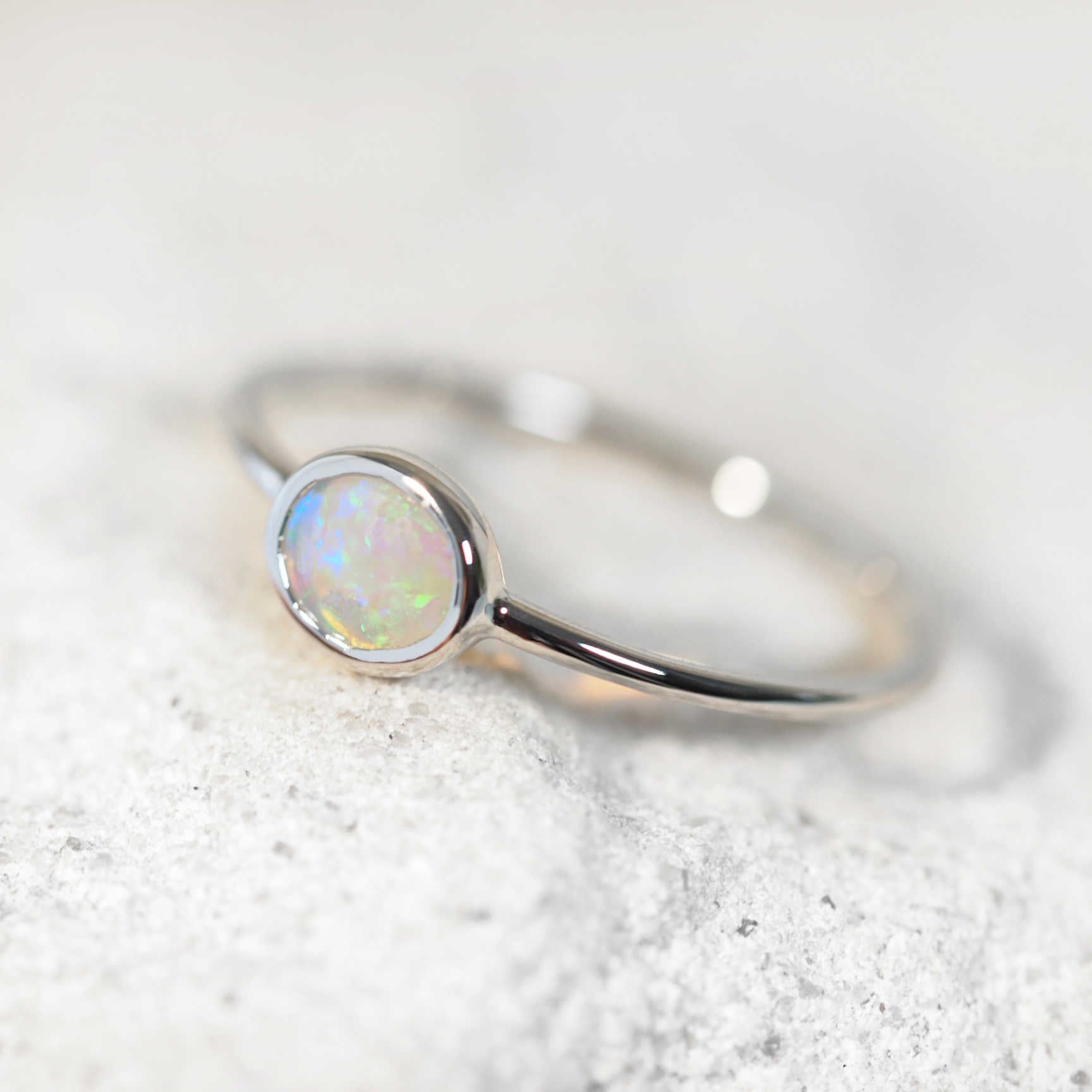 Delicate white gold opal ring featuring vibrant Australian crystal opal in asymmetrical design