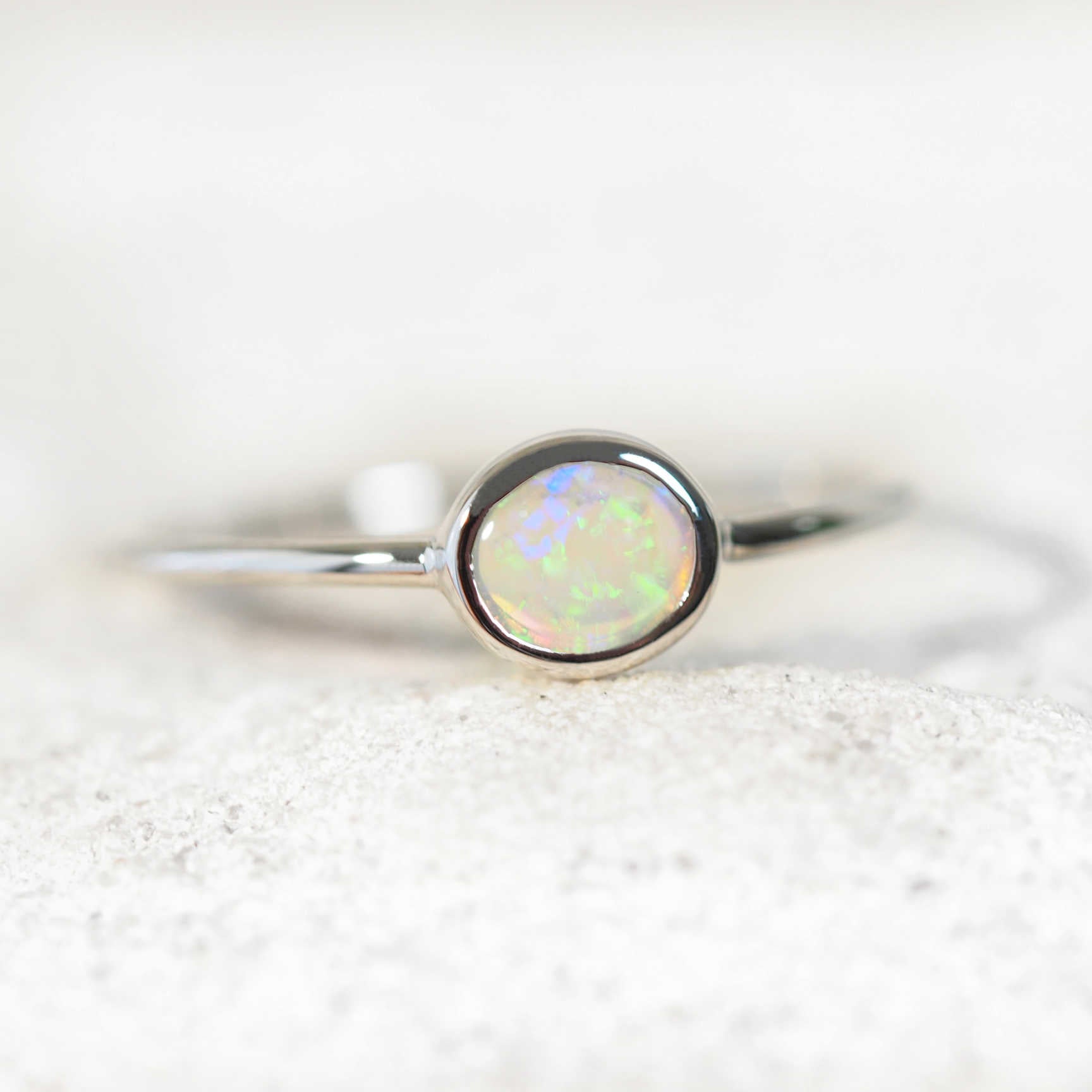 lose-up of side-set opal ring showing vivid green and blue play-of-colour