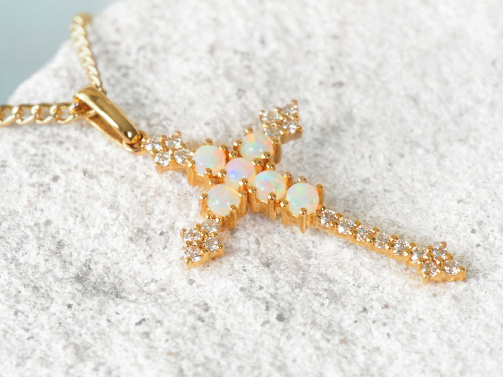 Gold necklace with opal stones on a white sandy background