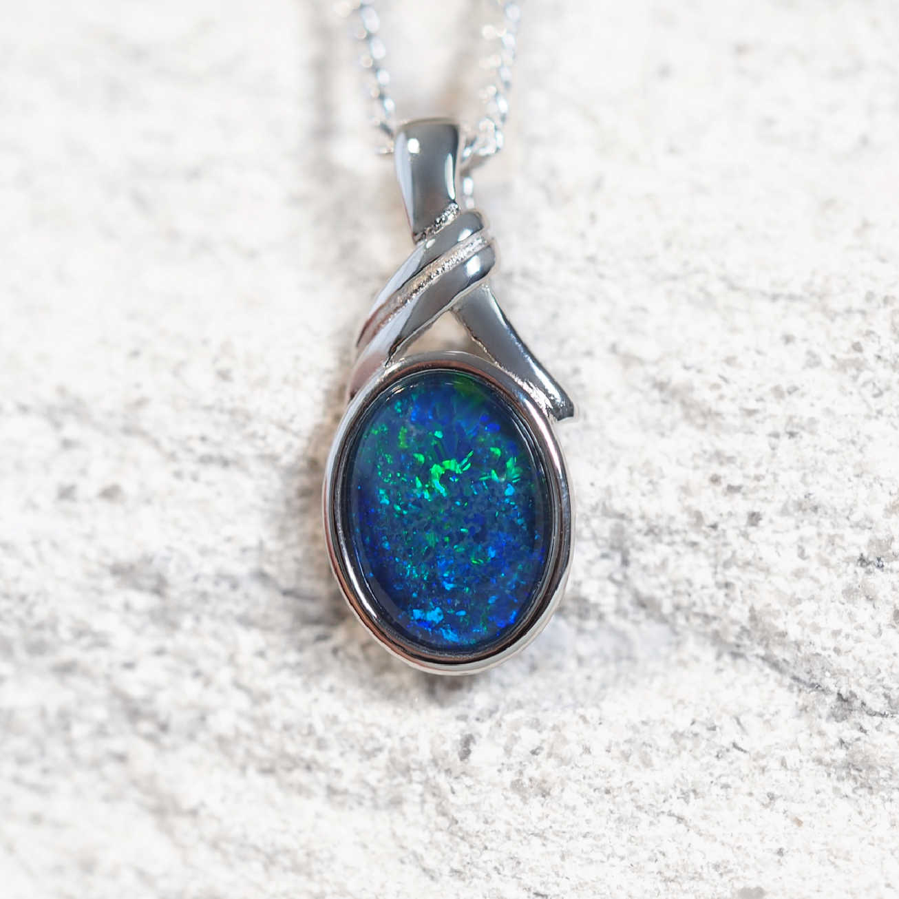'Malia Blue' opal pendant in sterling silver with decorative design and claw-set oval Australian triplet opal in vivid blue and green tones