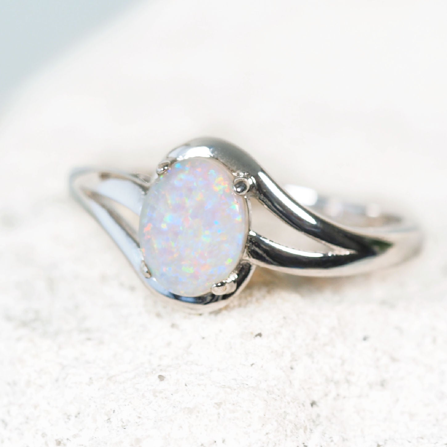Silver ring with a white opal stone on a light background