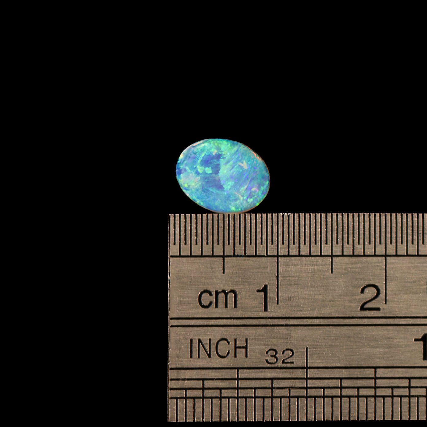 Opal stone with a wooden ruler for scale on a black background