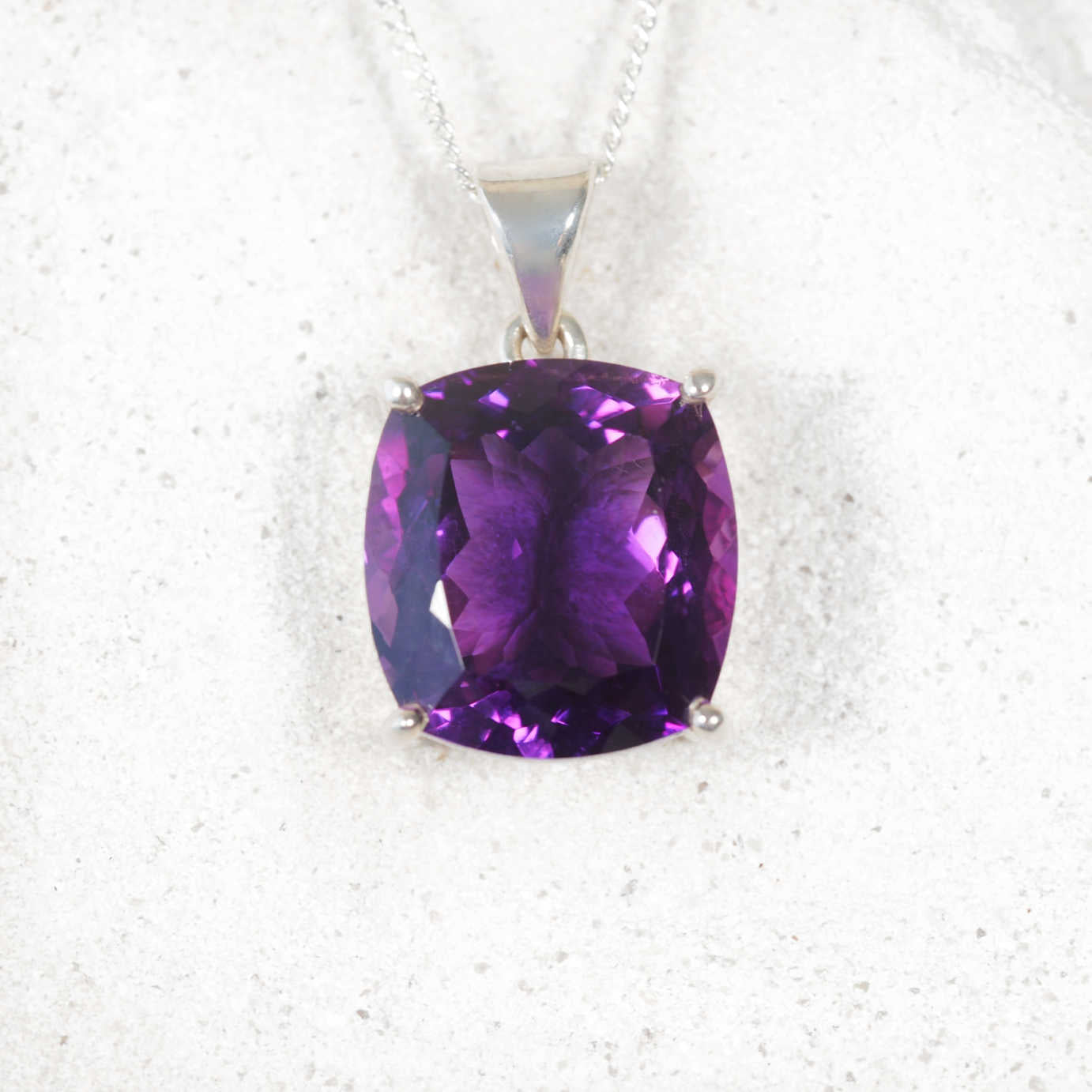 Faceted square Amethyst pendant with claw-style silver frame, displaying vibrant purple hues