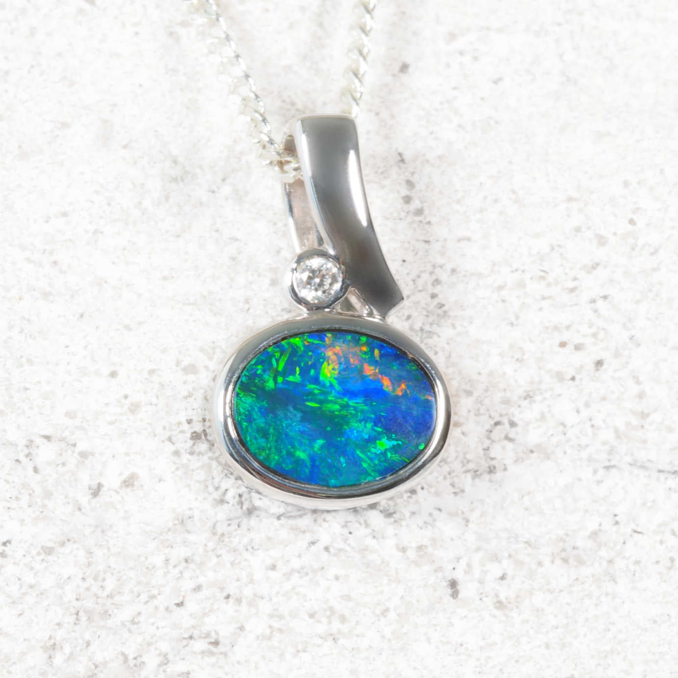 Opal pendant with white gold setting on a white background