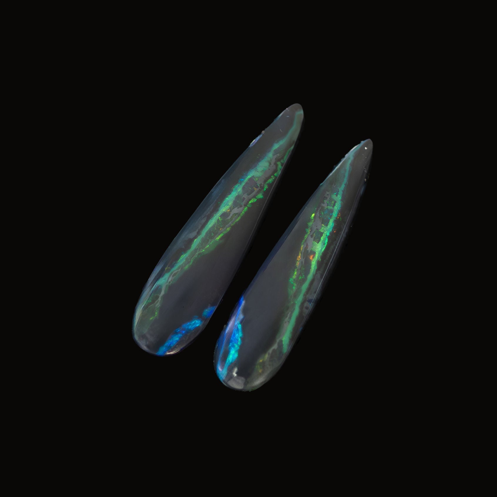 Black opal stone pair with colorful internal patterns on a black background