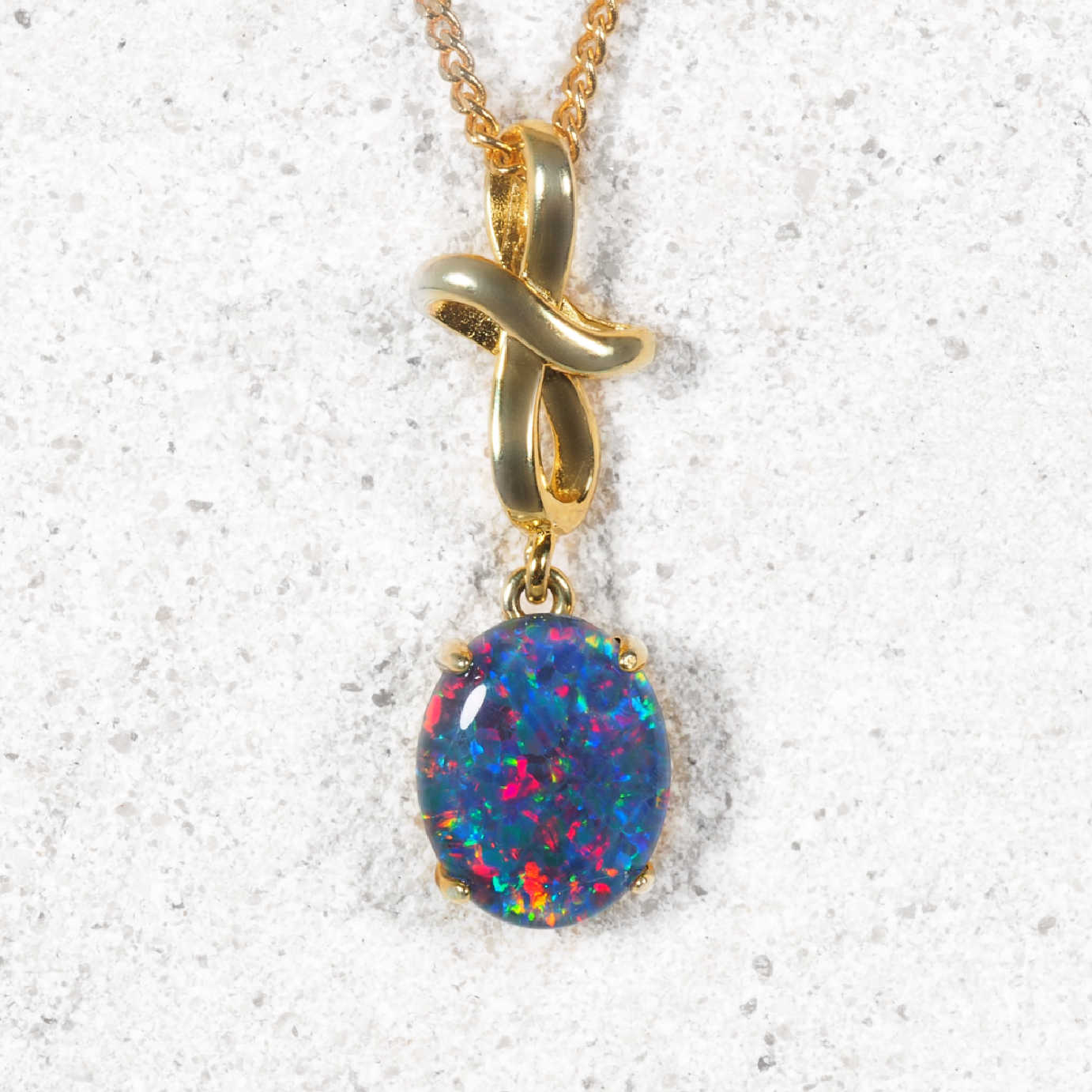 Gold necklace with a multi-colour opal pendant on a white background