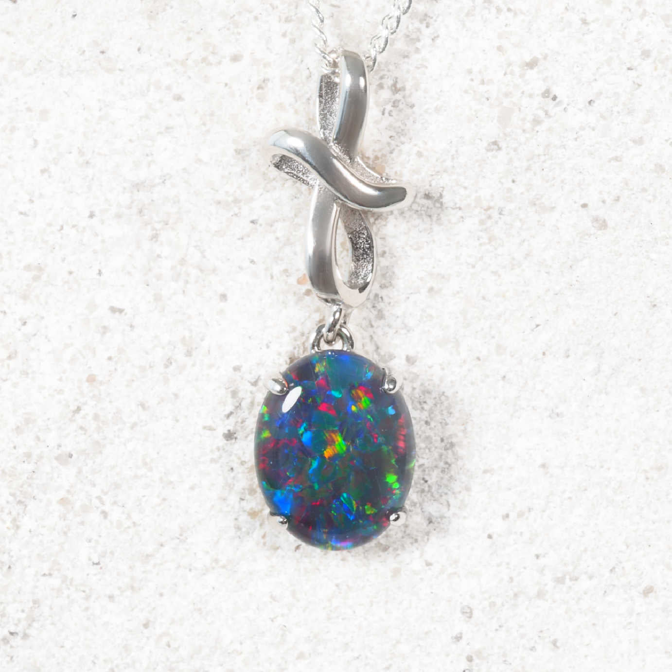 Opal pendant with silver 'X' design on a white background