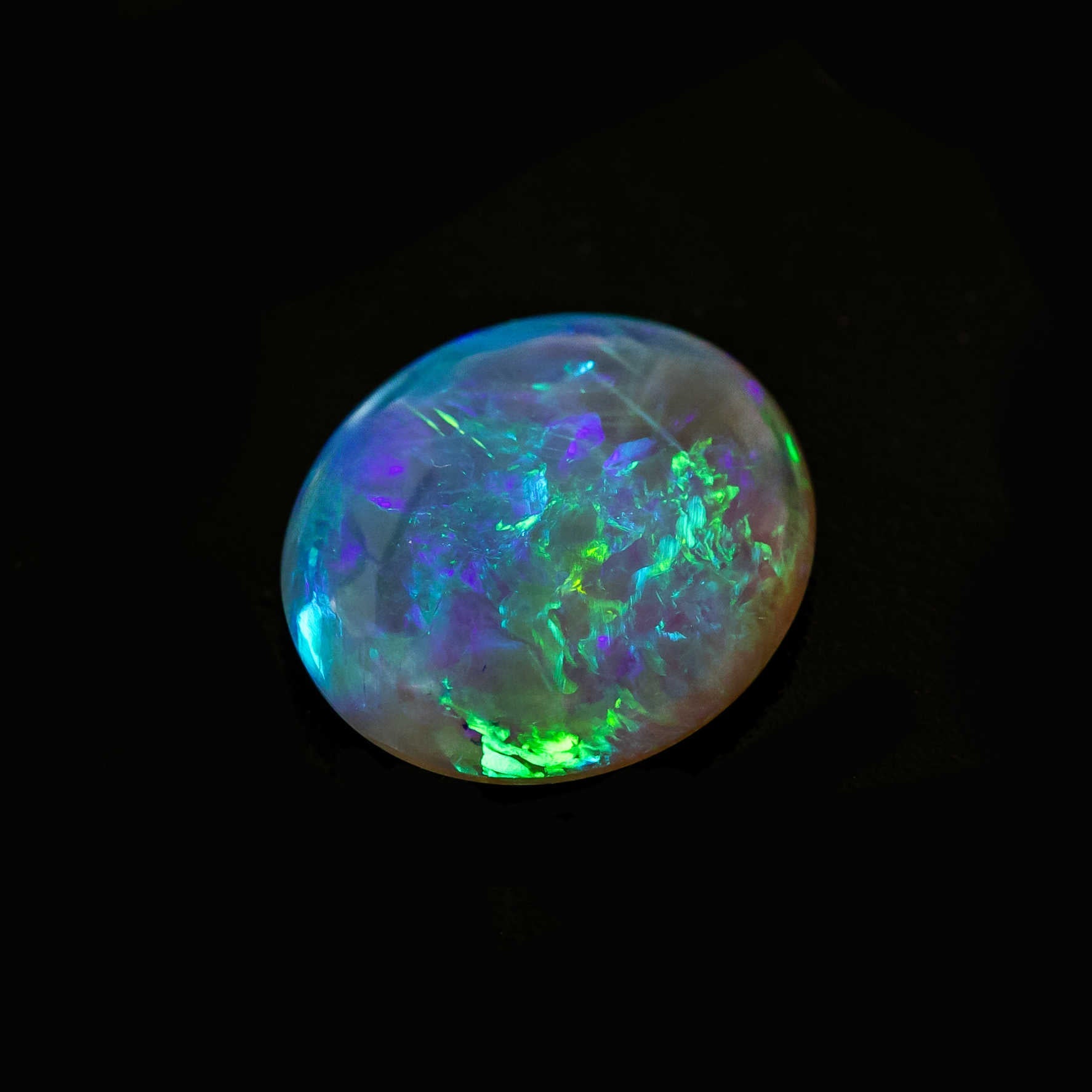 Oval cut opal showcasing vivid green and blue fire