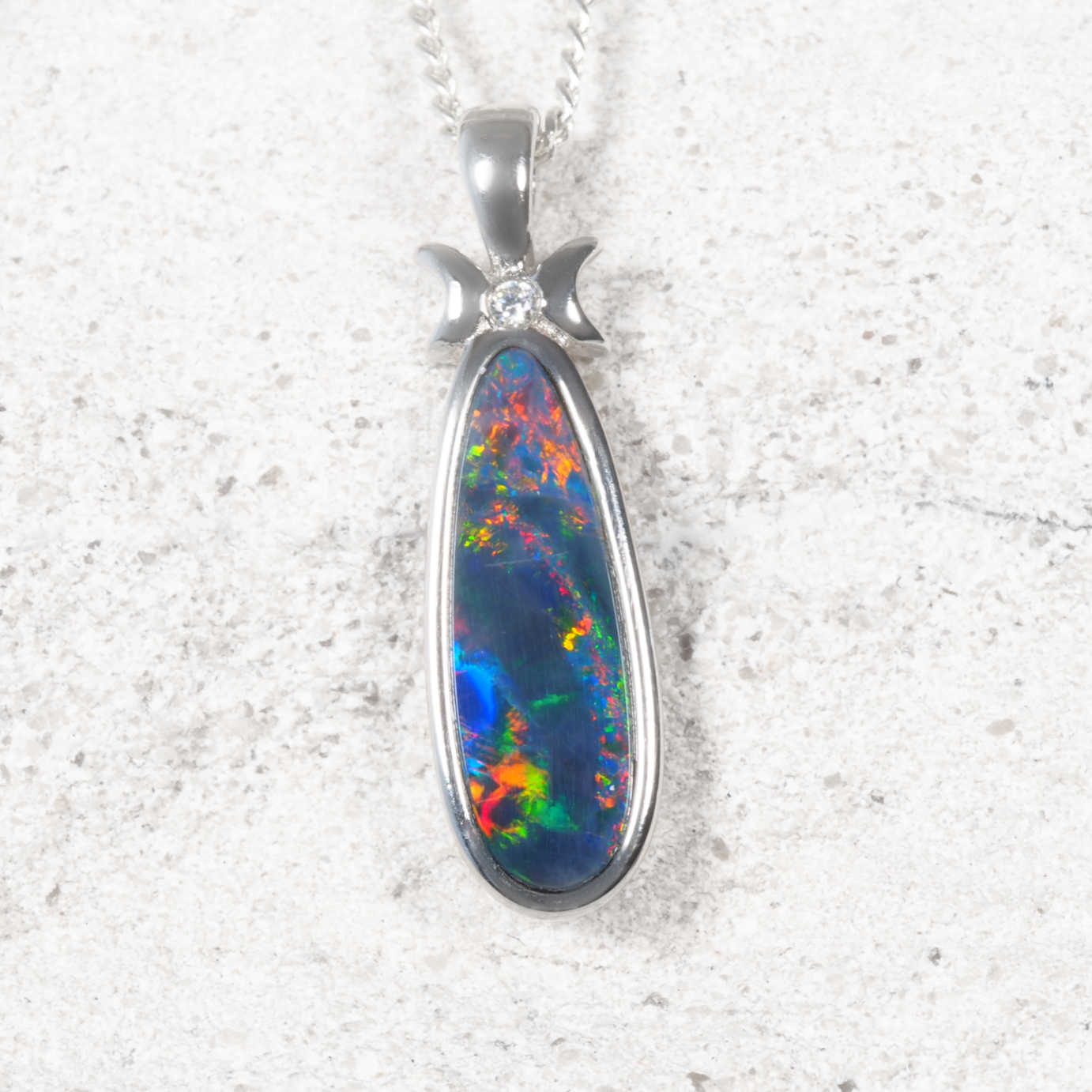 Opal pendant with silver setting on a textured white background