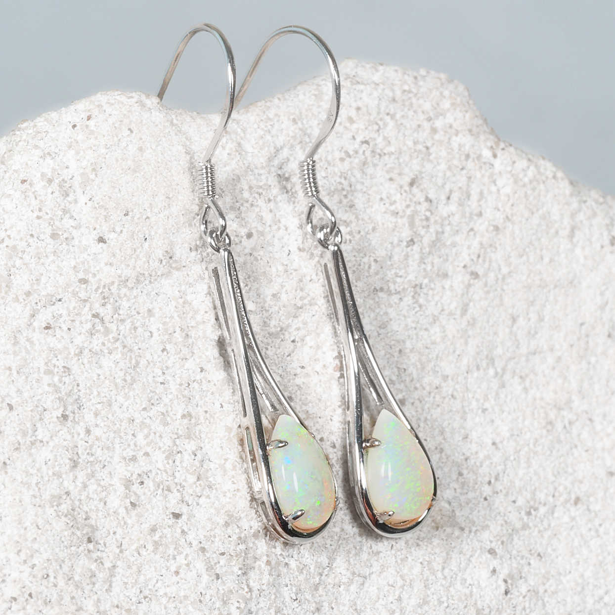 Silver earrings with green Australian opal stones on a textured surface