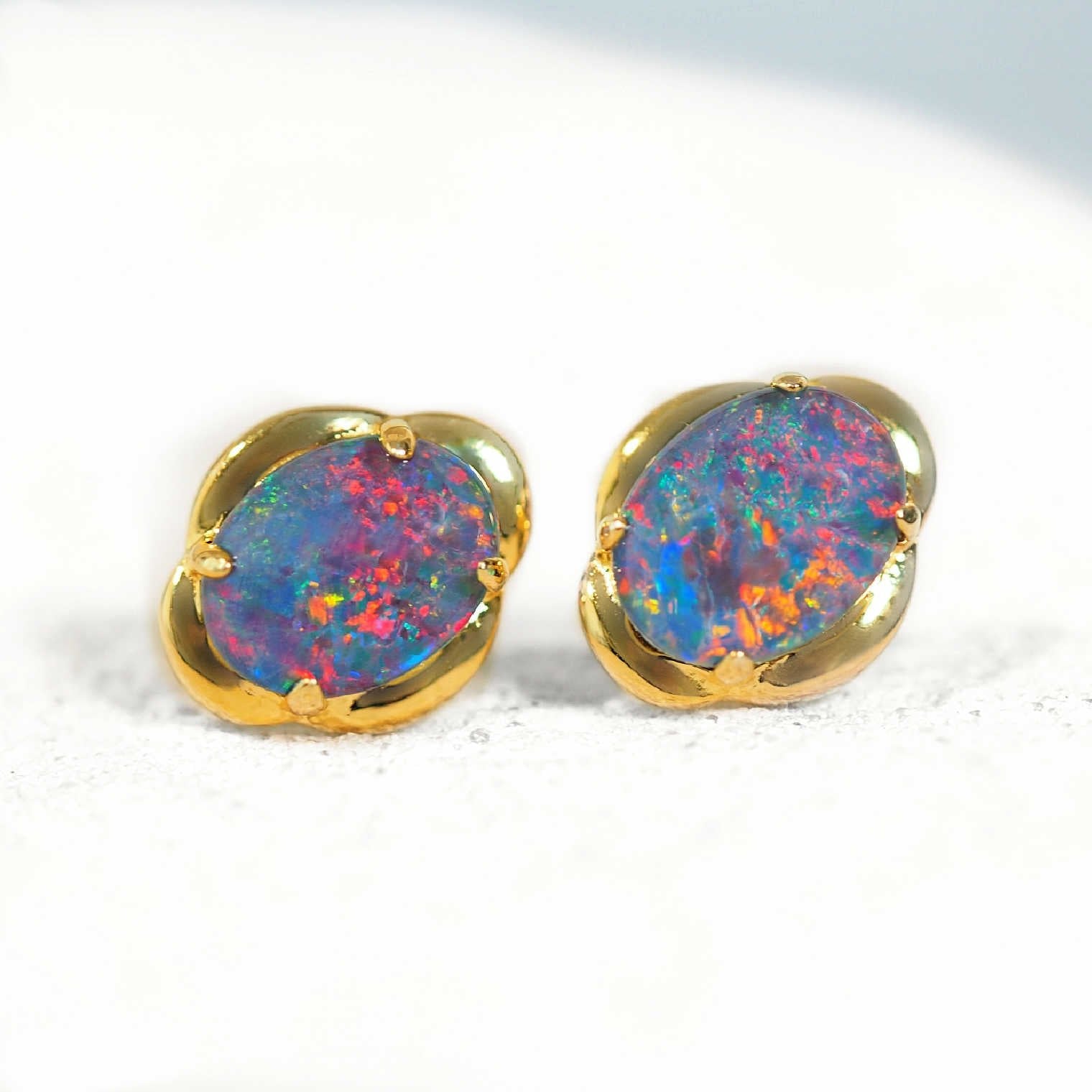Pair of opal stud earrings with gold setting on a white background