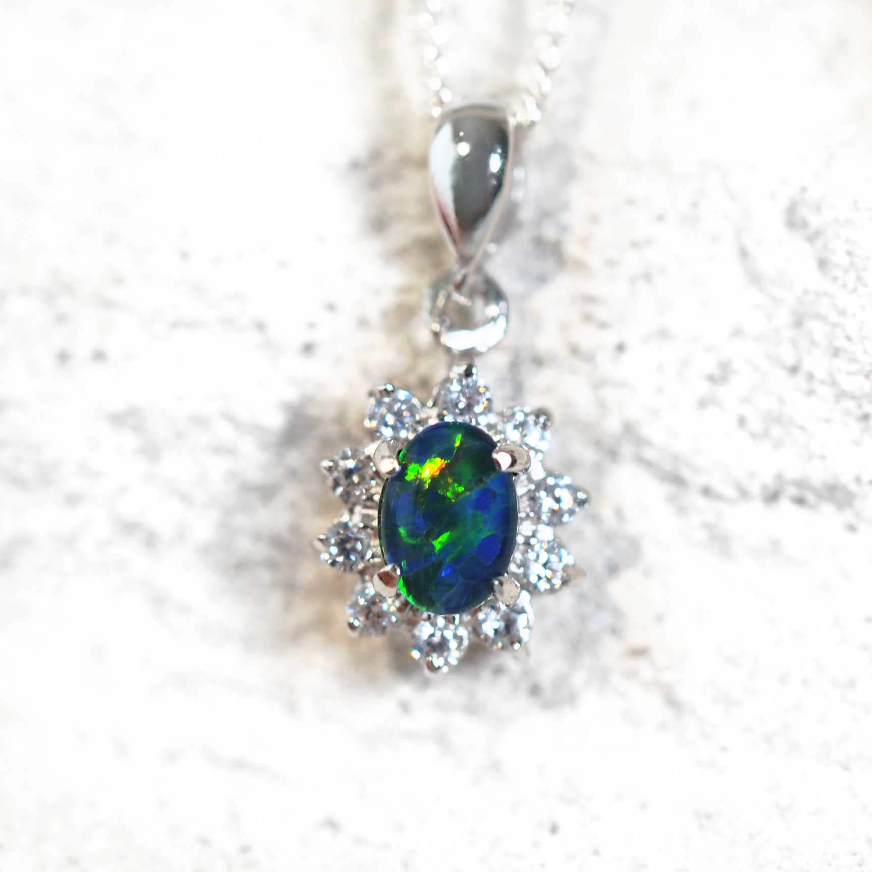 opal pendant set with a blue and green opal and twn cubic zirconias