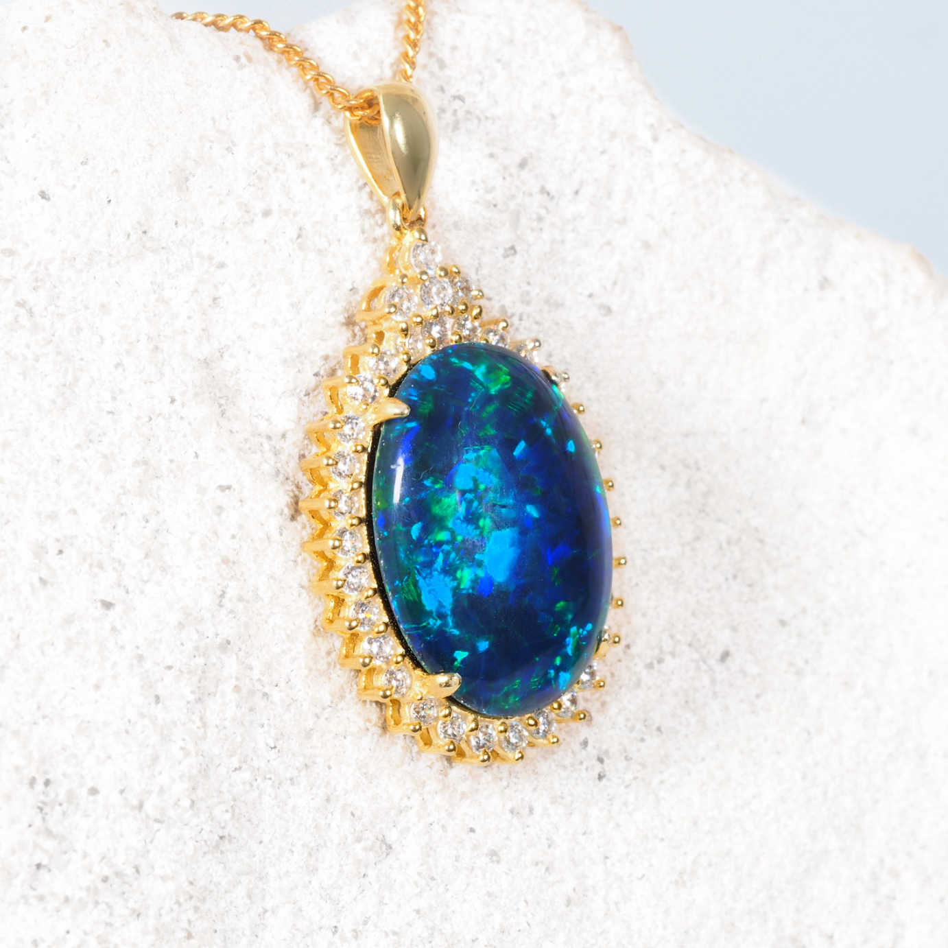 Blue statement opal pendant necklace on a white stone background