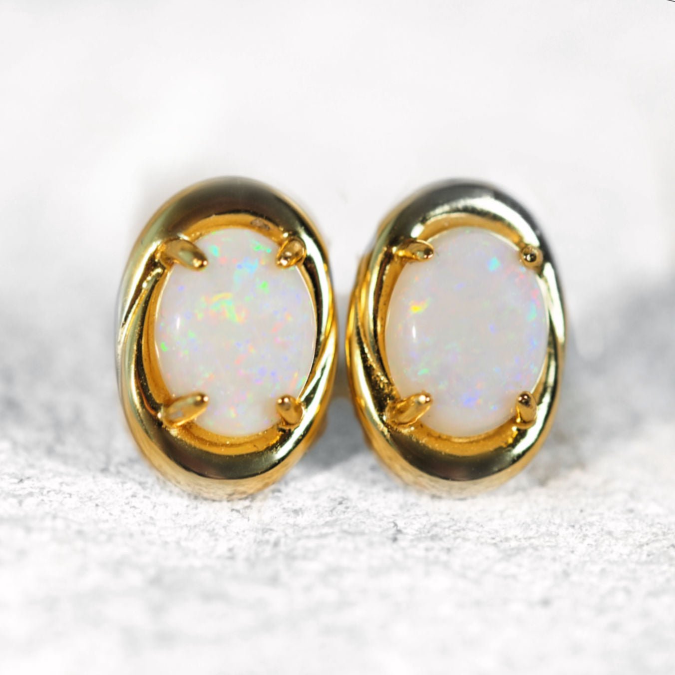 Pair of gold earrings with opal stones on a white background