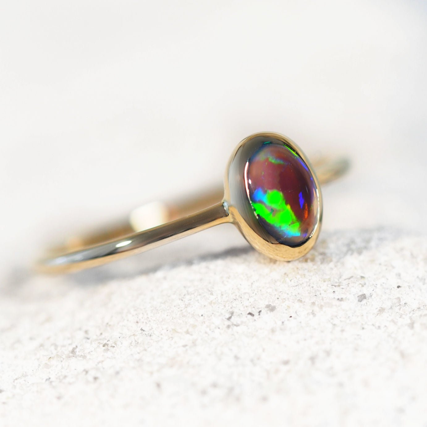 14ct yellow gold opal ring with a colorful opal stone on a white background